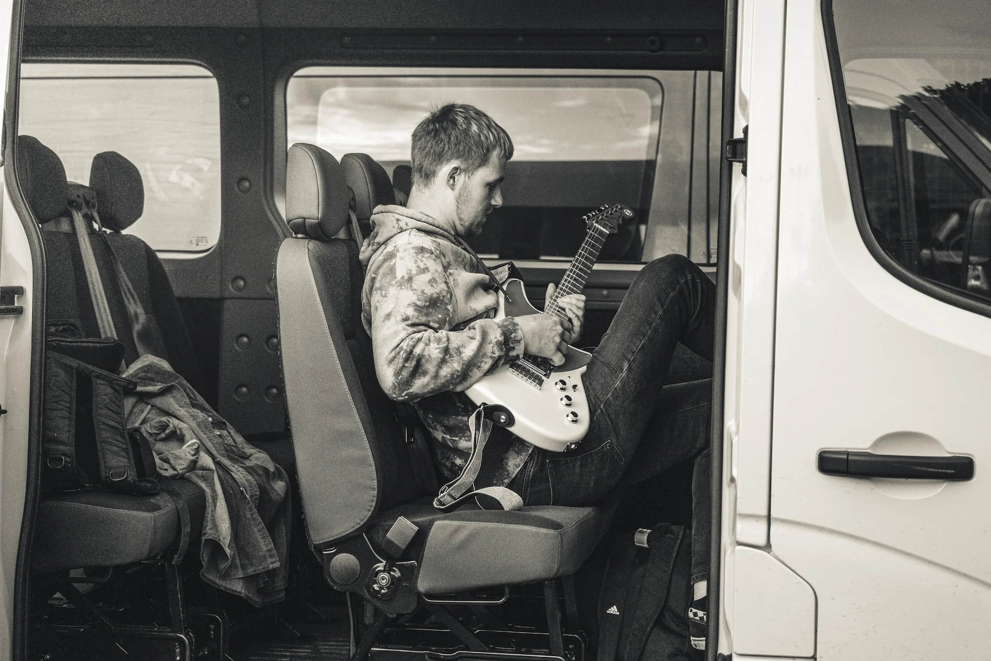 Portrétní fotografie sedícího kytaristy před vystoupením. Plzeň.