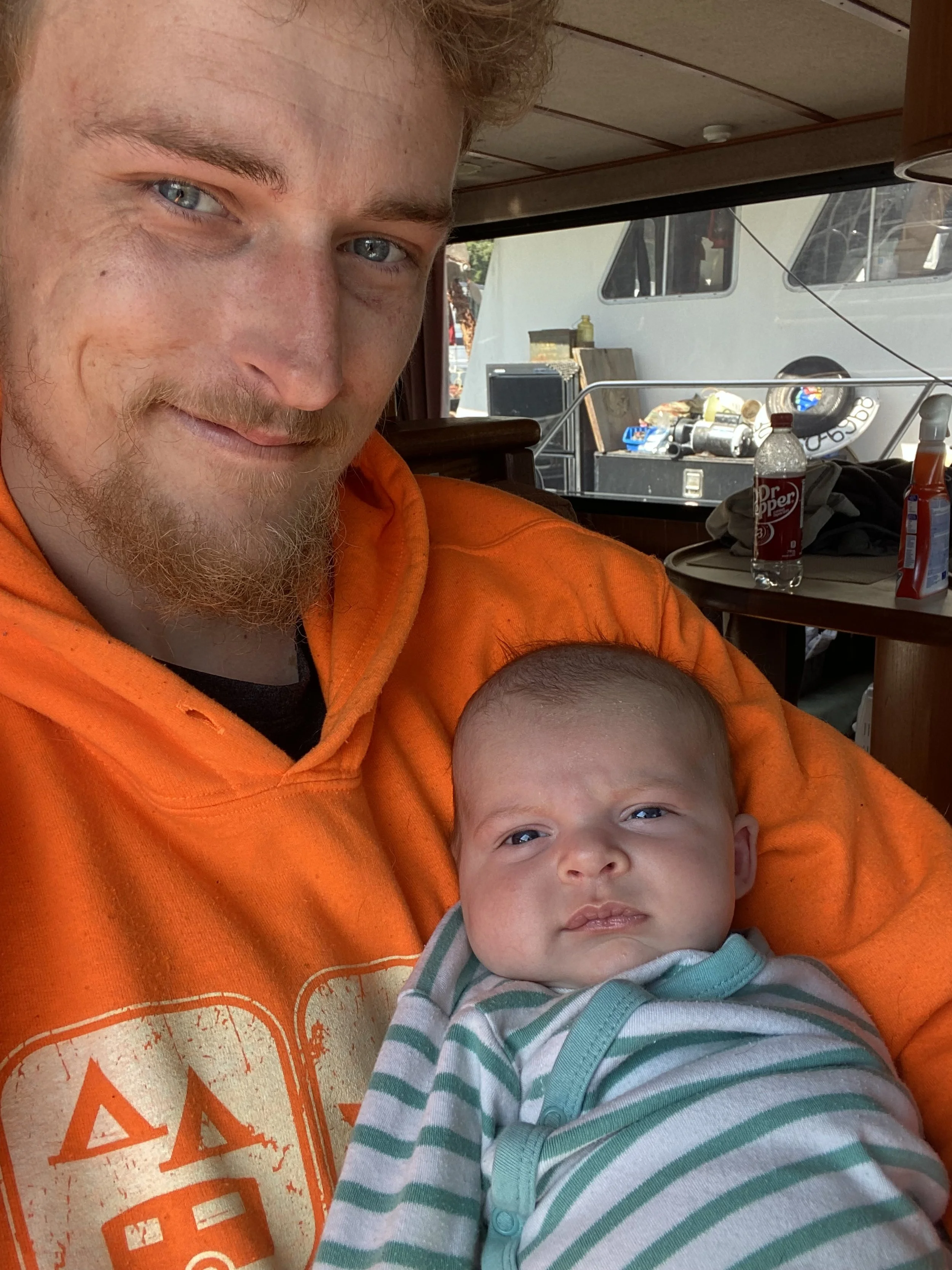 Founder Christopher James Ron Dushko, holding his Daughter Charlotte Dushko with a serious expression, Aboard his vessel "Morning Mist 1".