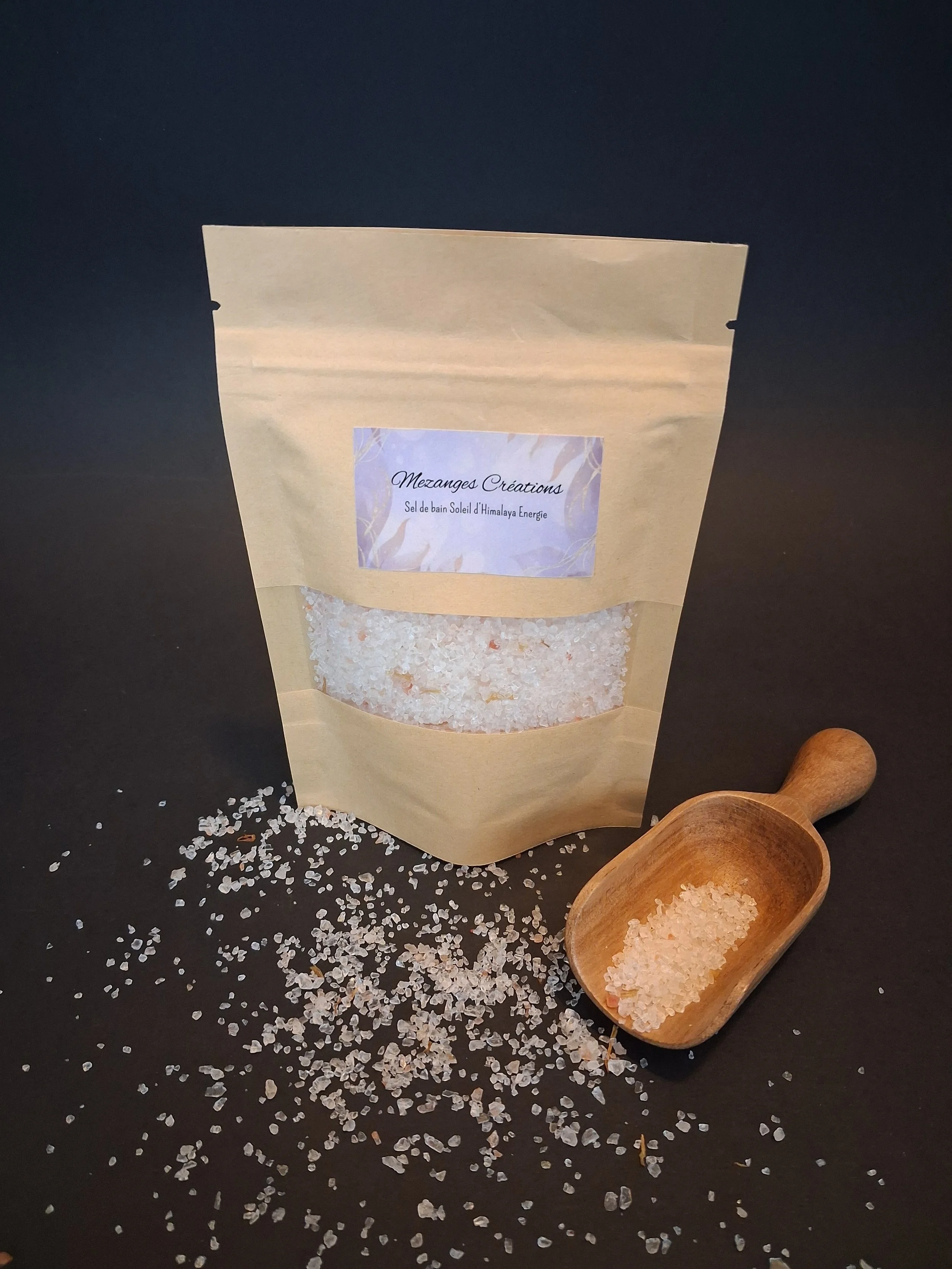 Sachet de sel de bain naturel avec un petit moulin en bois contenant du sel, sur fond noir.