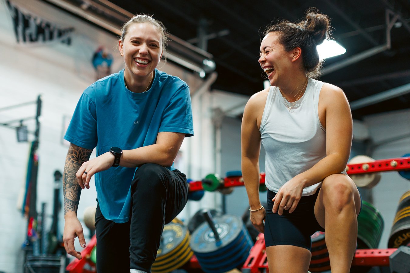 Supportive trainer-client relationship. Woman personal trainer and client smiling together during a one-on-one strength training session at a gym in Washington, DC, at Navy Yard SW location.