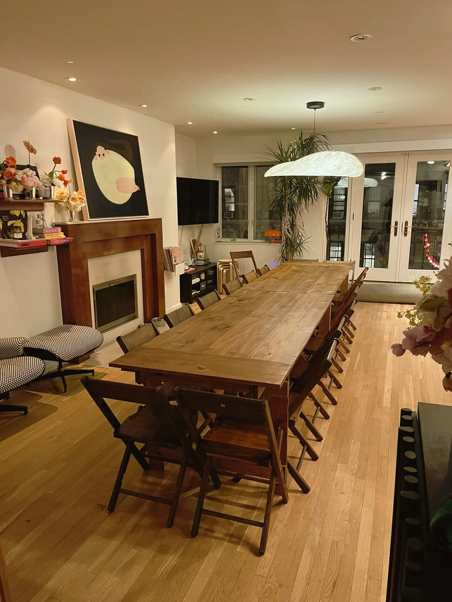 Long handmade folding farm table surrounded by vintage wooden folding chairs at a birthday dinner in a West Village NYC apartment.