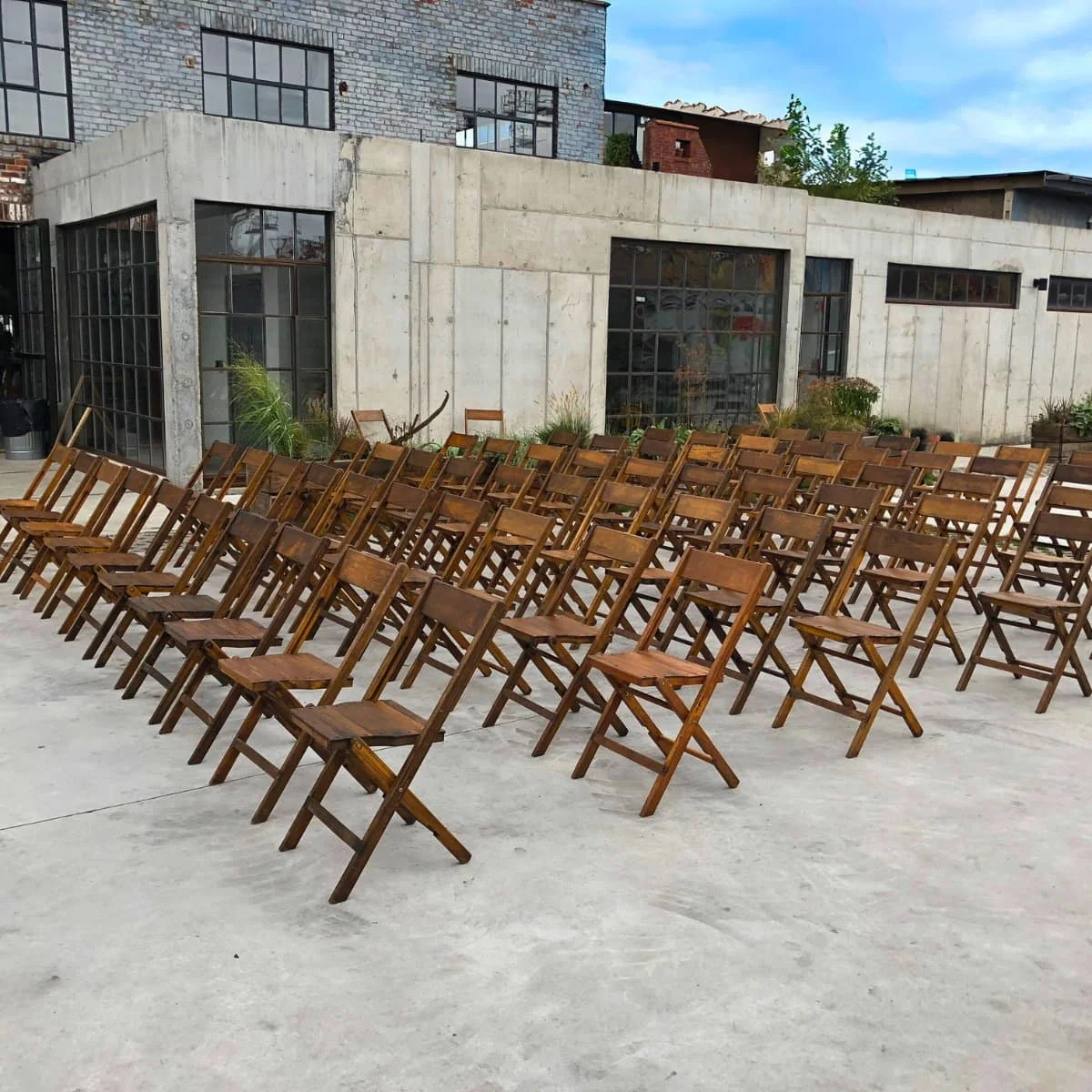 KRAUS dark-finish vintage wooden folding chairs arranged for an outdoor ceremony