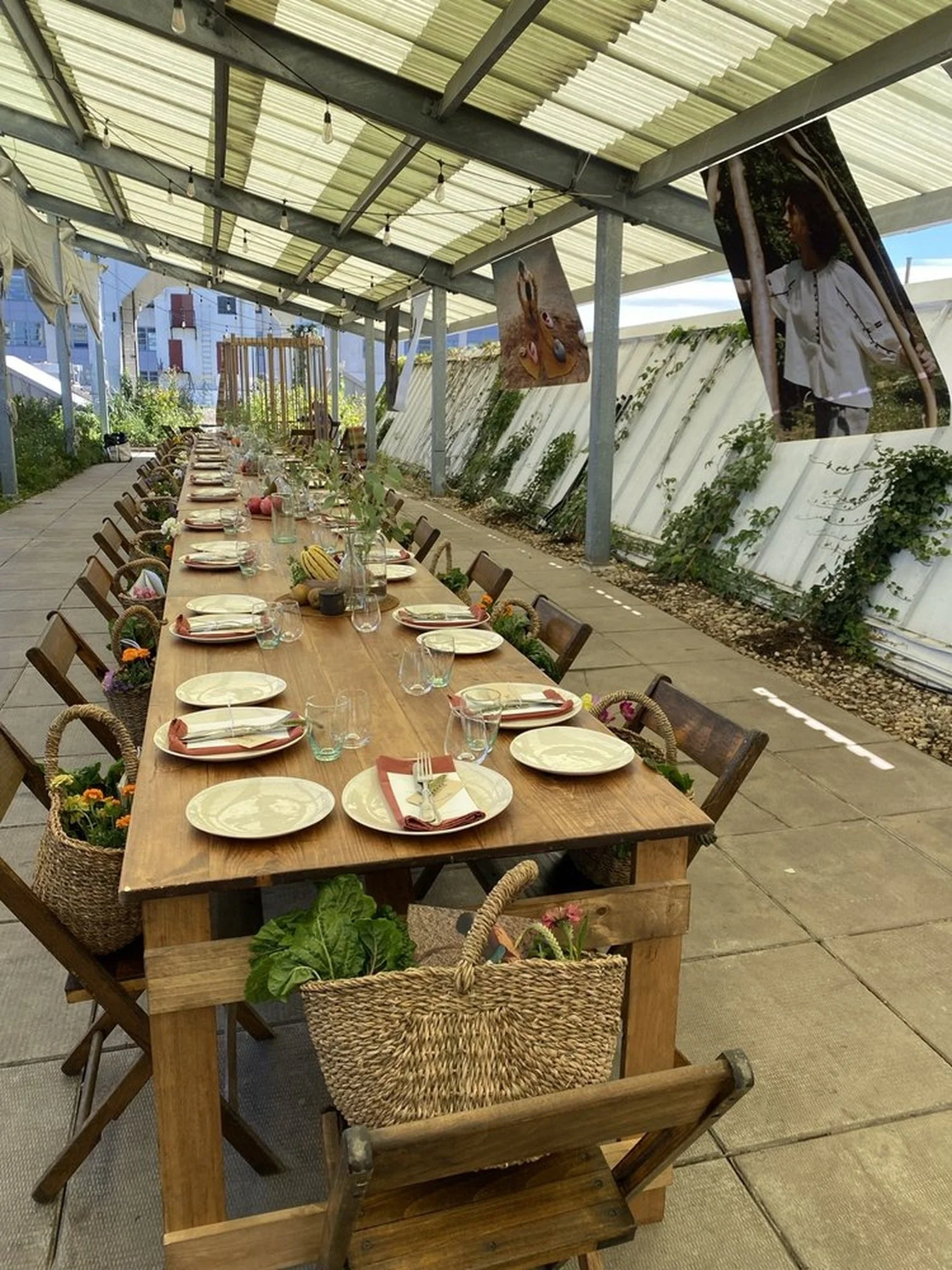 A long banquet of handmade wooden farm tables and vintage wooden folding chairs set for a magazine lunch event at Brooklyn Grange on the roof garden.