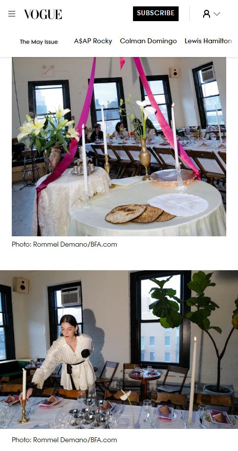 Decorated dining table with candles and floral arrangements, set for a meal in a bright, modern room with large windows. A woman in a white dress is arranging the table.