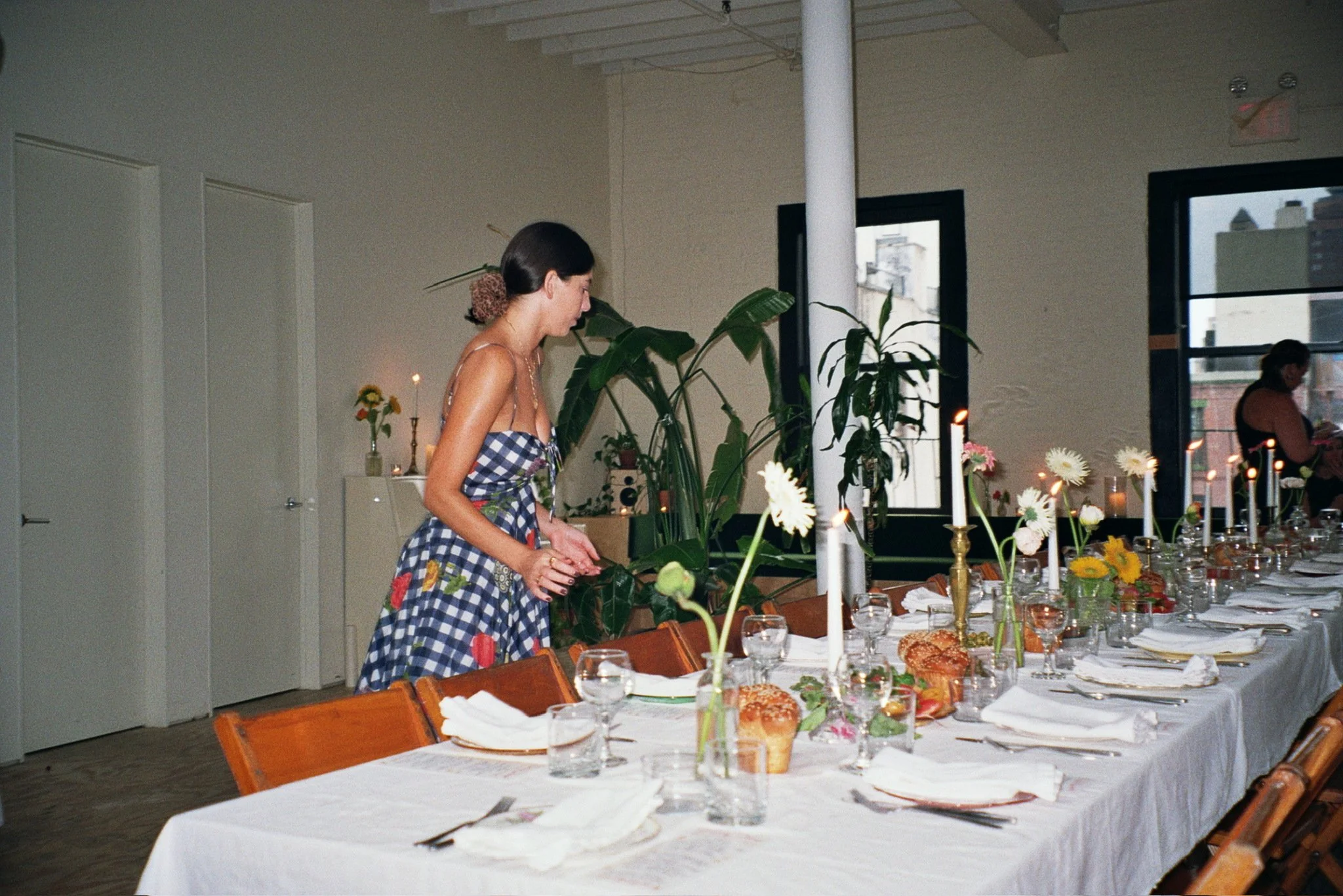 A long dining table with vintage wooden folding chairs set for a Shabbos dinner hosted by Shtick NYC in a Chinatown event space.
