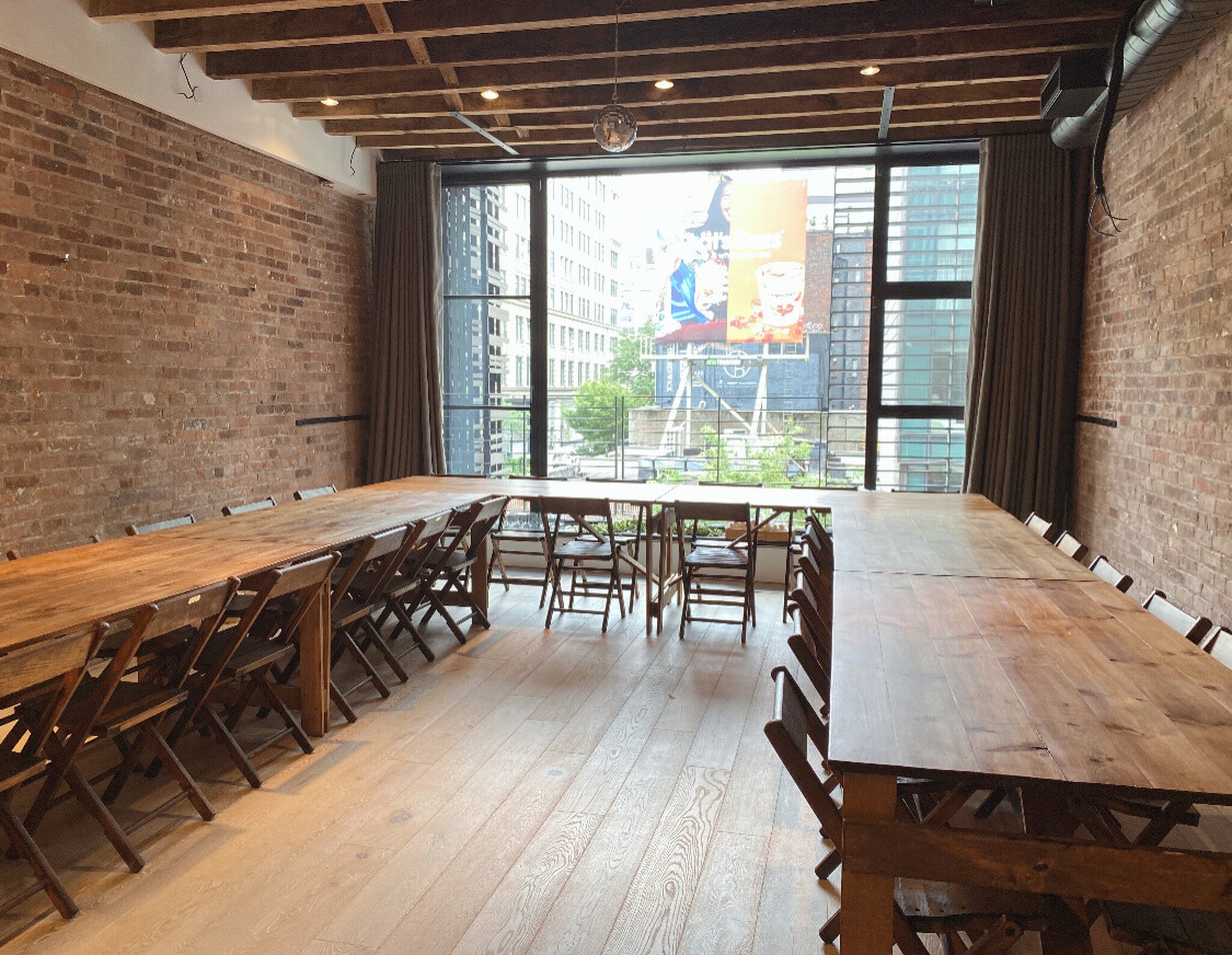 Handmade folding farm tables with vintage wooden folding chairs arranged in a long banquet layout inside a Tribeca townhouse dining space.