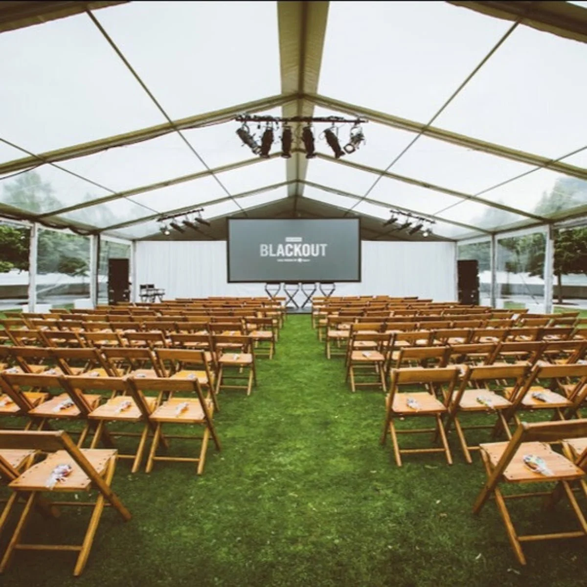 KRAUS light-finish vintage wooden folding chairs arranged for a screening under a tent