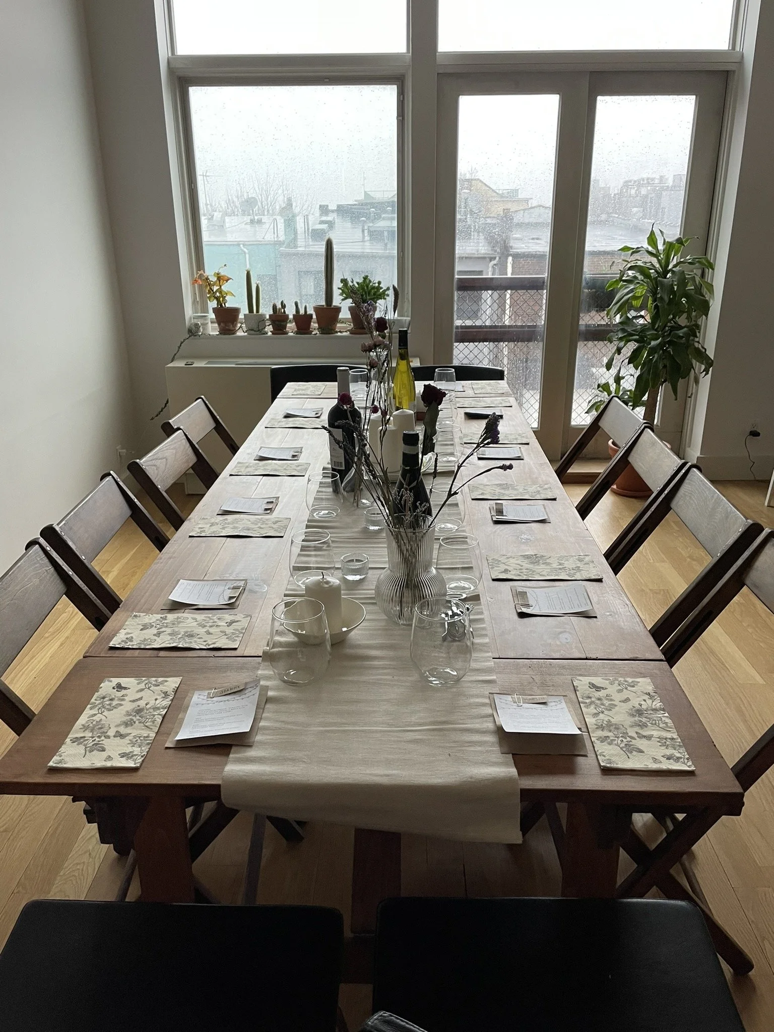 Handmade folding farm table with vintage wooden folding chairs and end leaf extensions set for a birthday dinner in a Bushwick Brooklyn apartment.