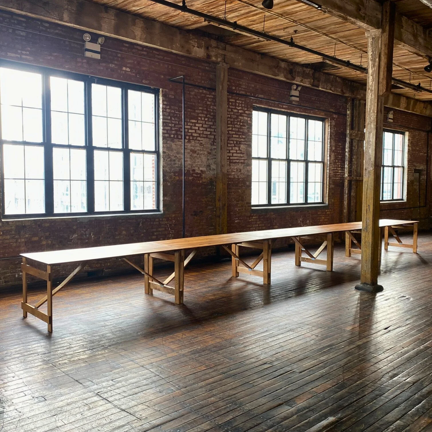 KRAUS handmade folding farm tables set for a long banquet in an industrial event space
