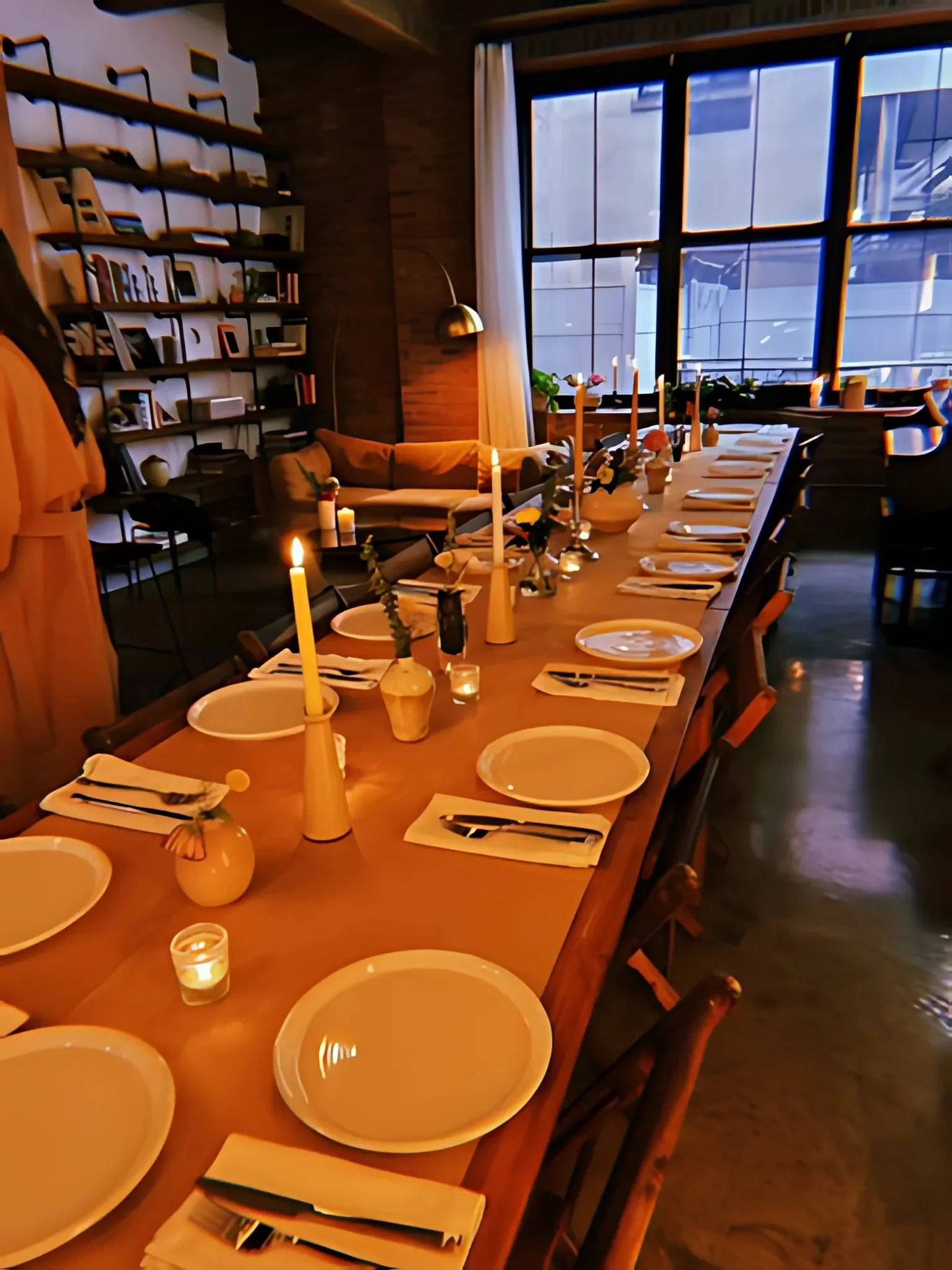 Handmade folding farm tables with vintage wooden folding chairs arranged in a long banquet layout for a dinner party in a Greenpoint Brooklyn loft.