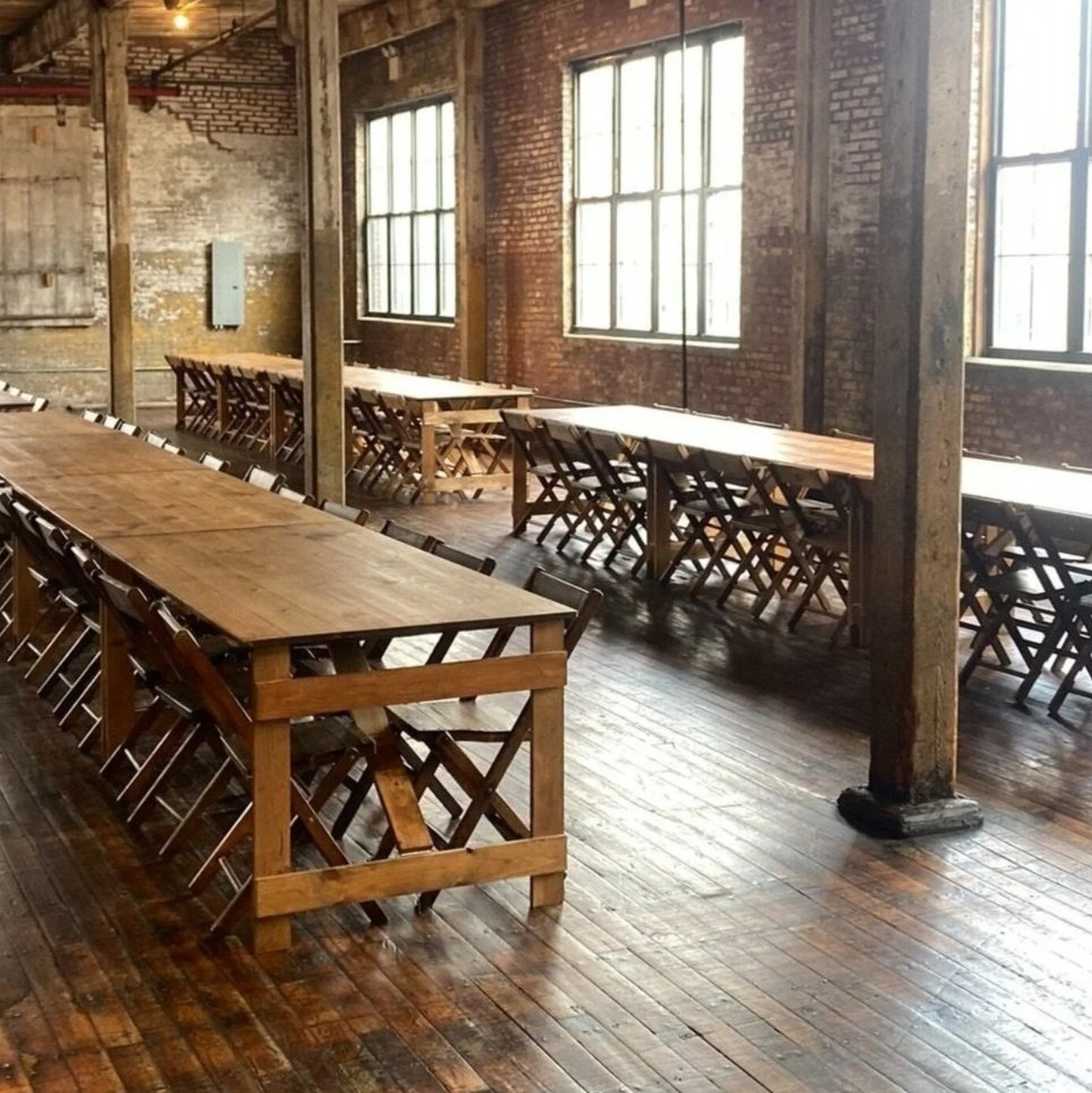 KRAUS folding farm table and vintage wooden chairs set for a banquet in an industrial loft venue