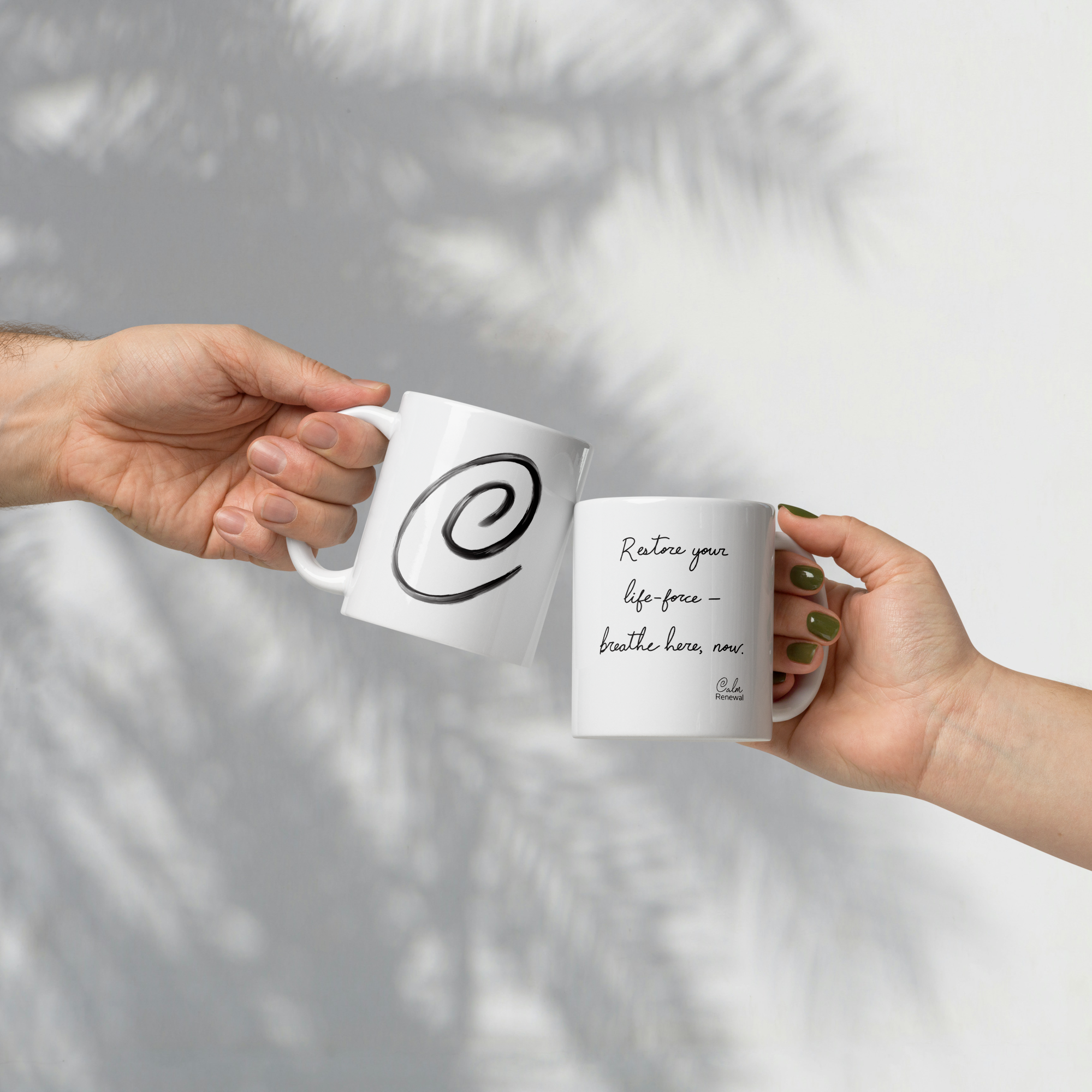 Close-up of a hand holding a white mug with a black spiral design, against a plain light-colored wall background.