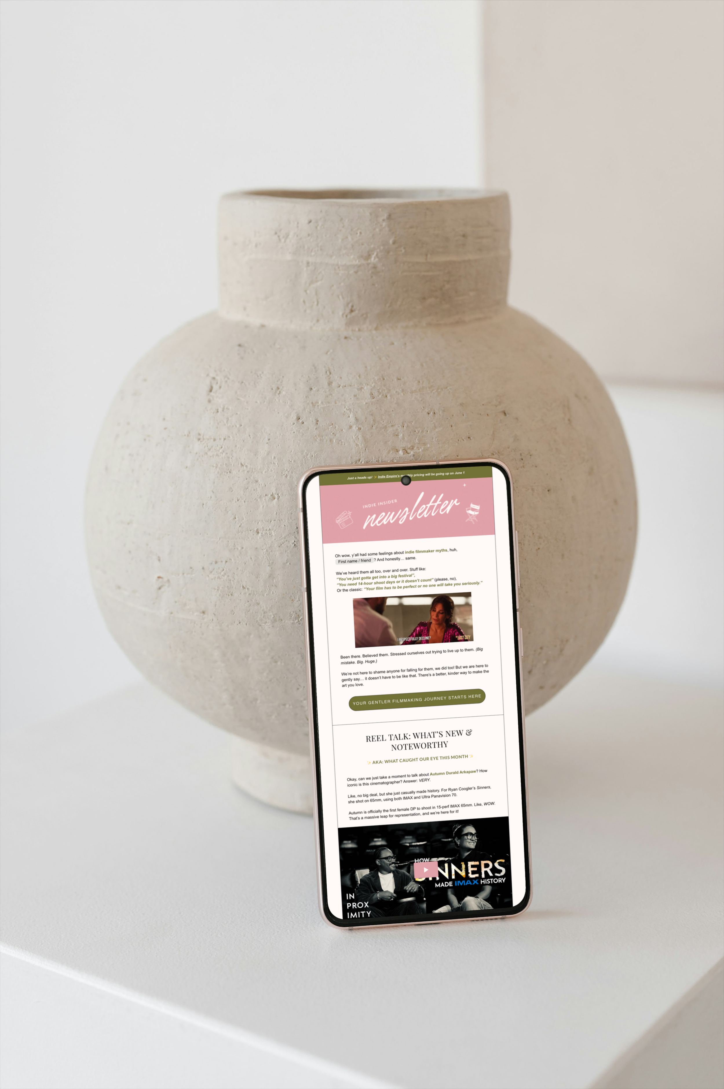 A phone against a ceramic vase displays the Indie Insider Newsletter covering indie filmmaking myths and new releases.
