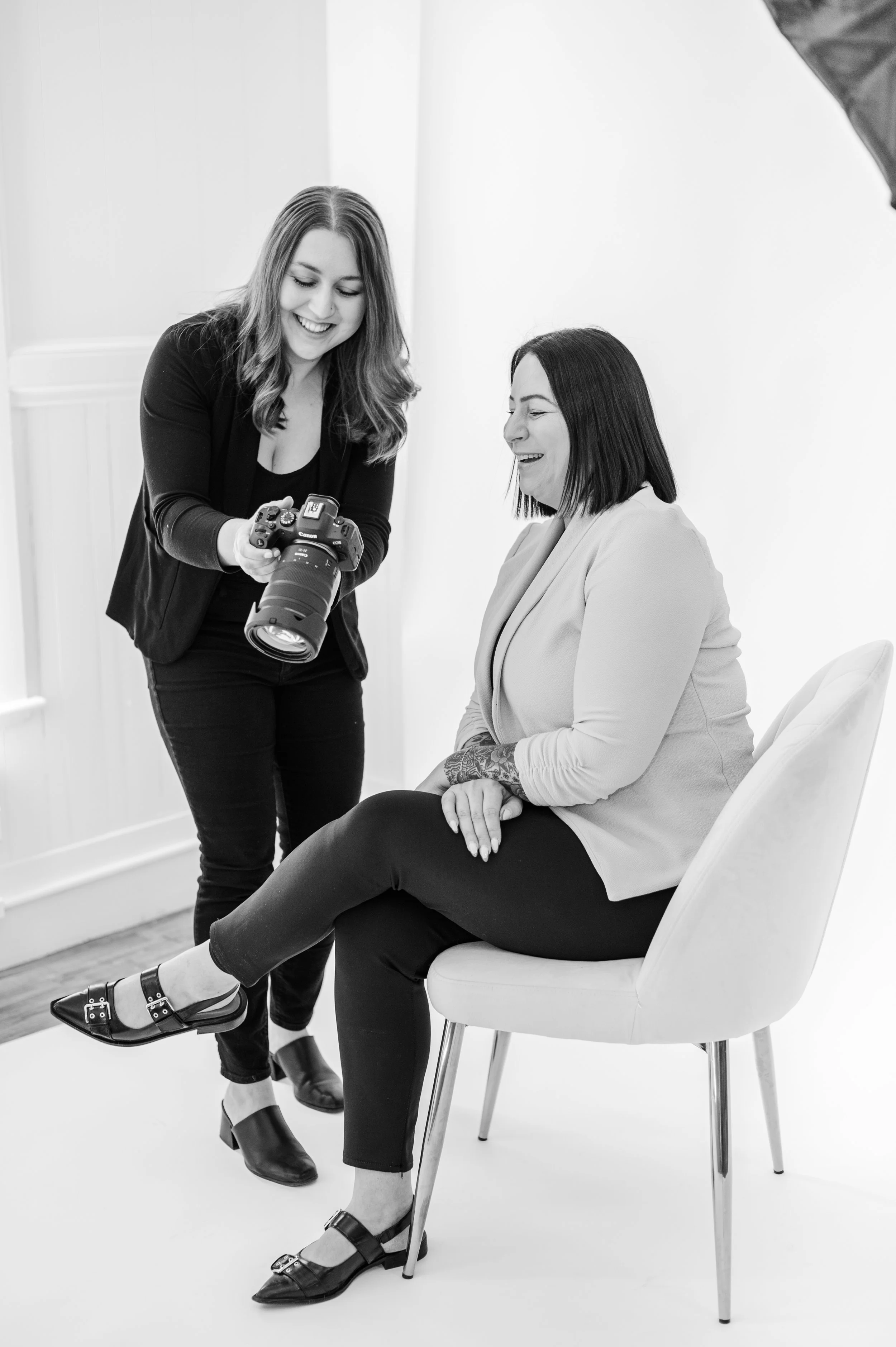 Rebecca Loomis shows a client the back of her camera during a brand photography session in her studio.