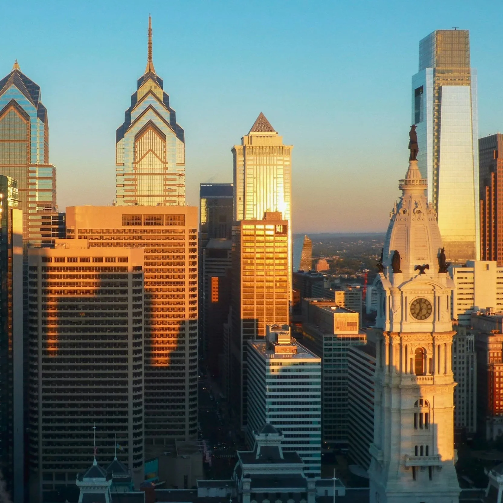 Sunset view of Philadelphia skyline with iconic buildings and William Penn statue atop city hall