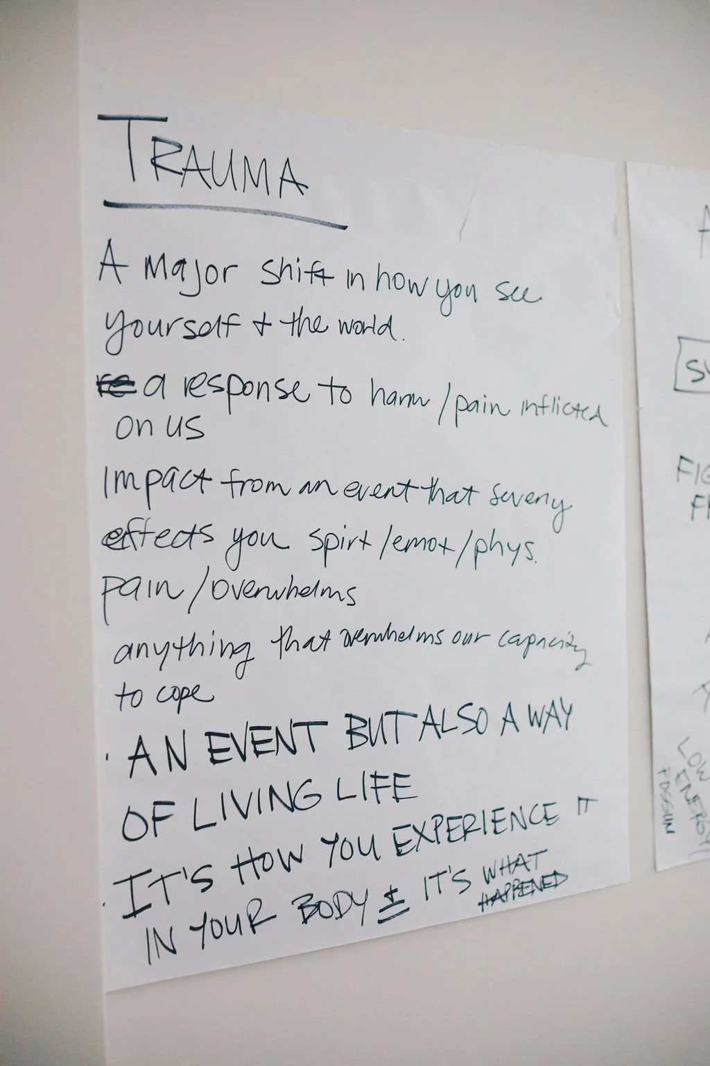 A handwritten poster titled 'Trauma' with notes about how trauma affects perceptions and body responses, emphasizing it as a way of living life and experiencing the body.