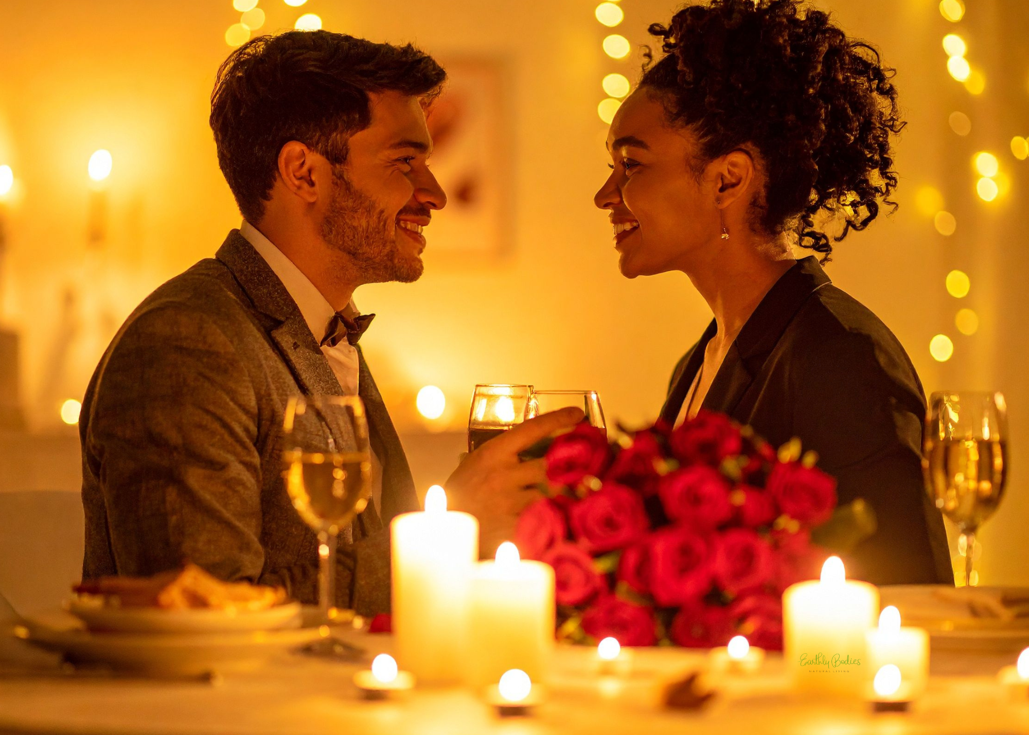 A romantic dinner scene with a man and woman smiling at each other, holding glasses of wine, surrounded by candles and a bouquet of red roses, with warm, golden lighting.