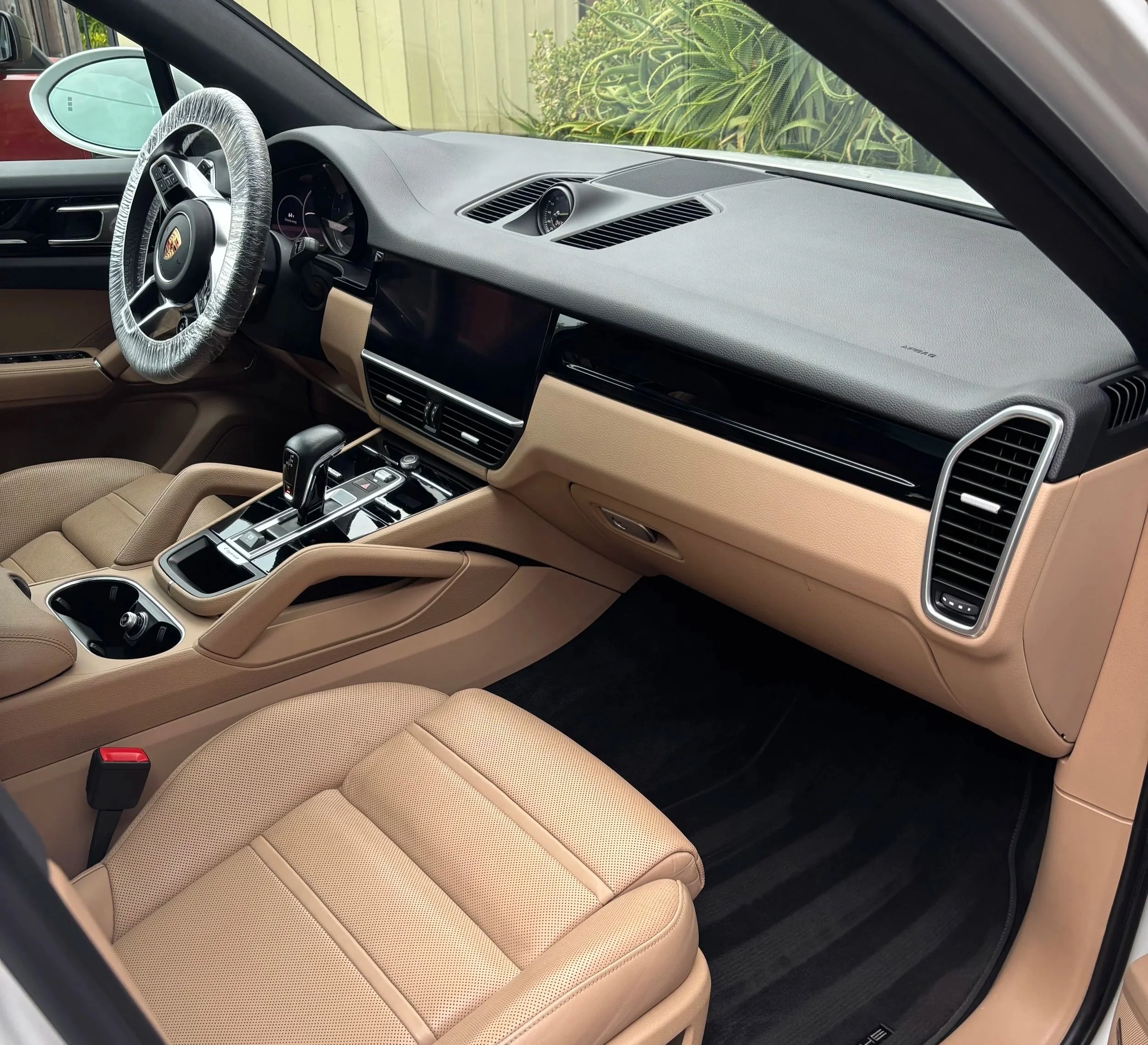 Interior of a luxury car with tan seats, a black dashboard, and a gear shifter on the center console.