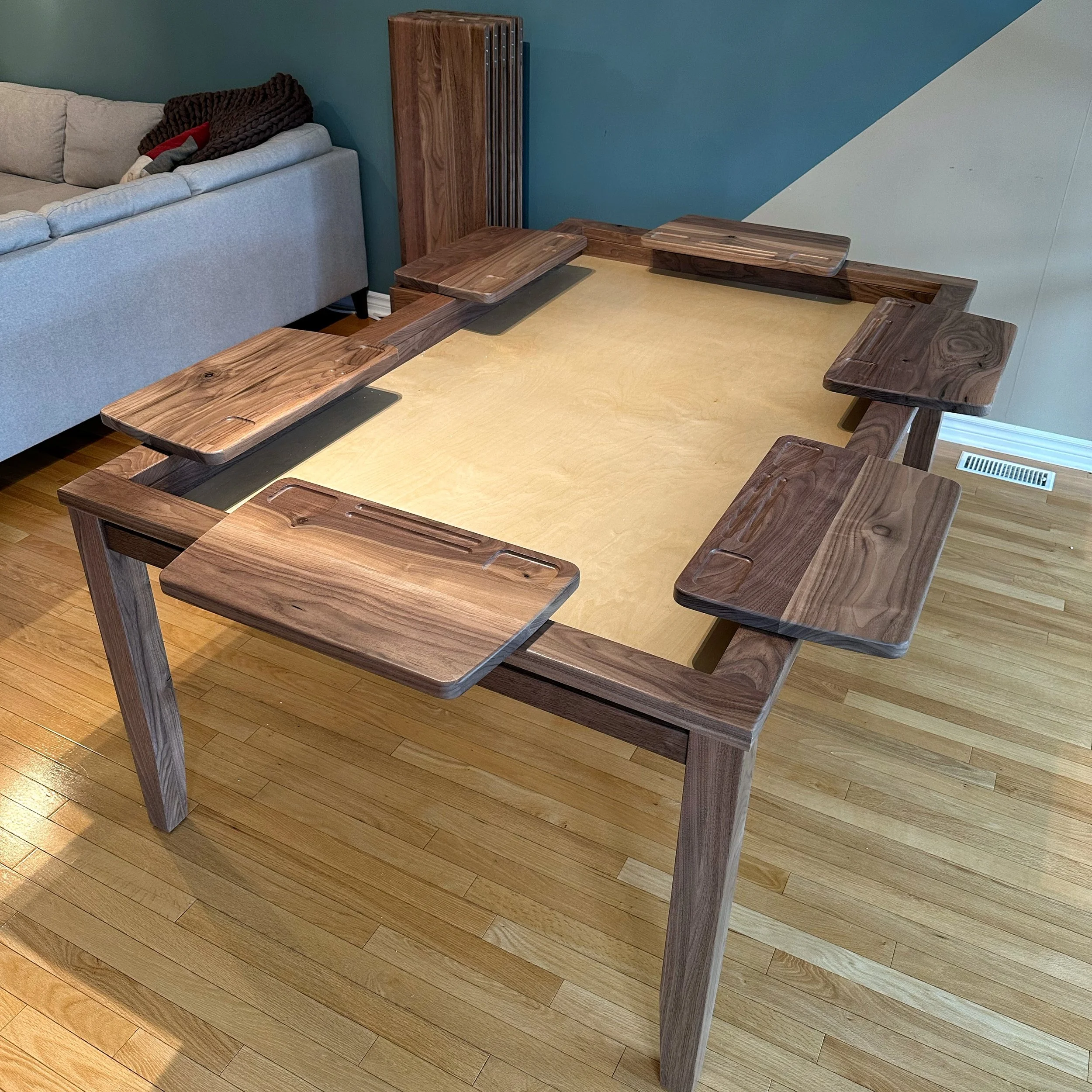 Corner view of a sleek wlanut game table with player station desks attached to the armrest