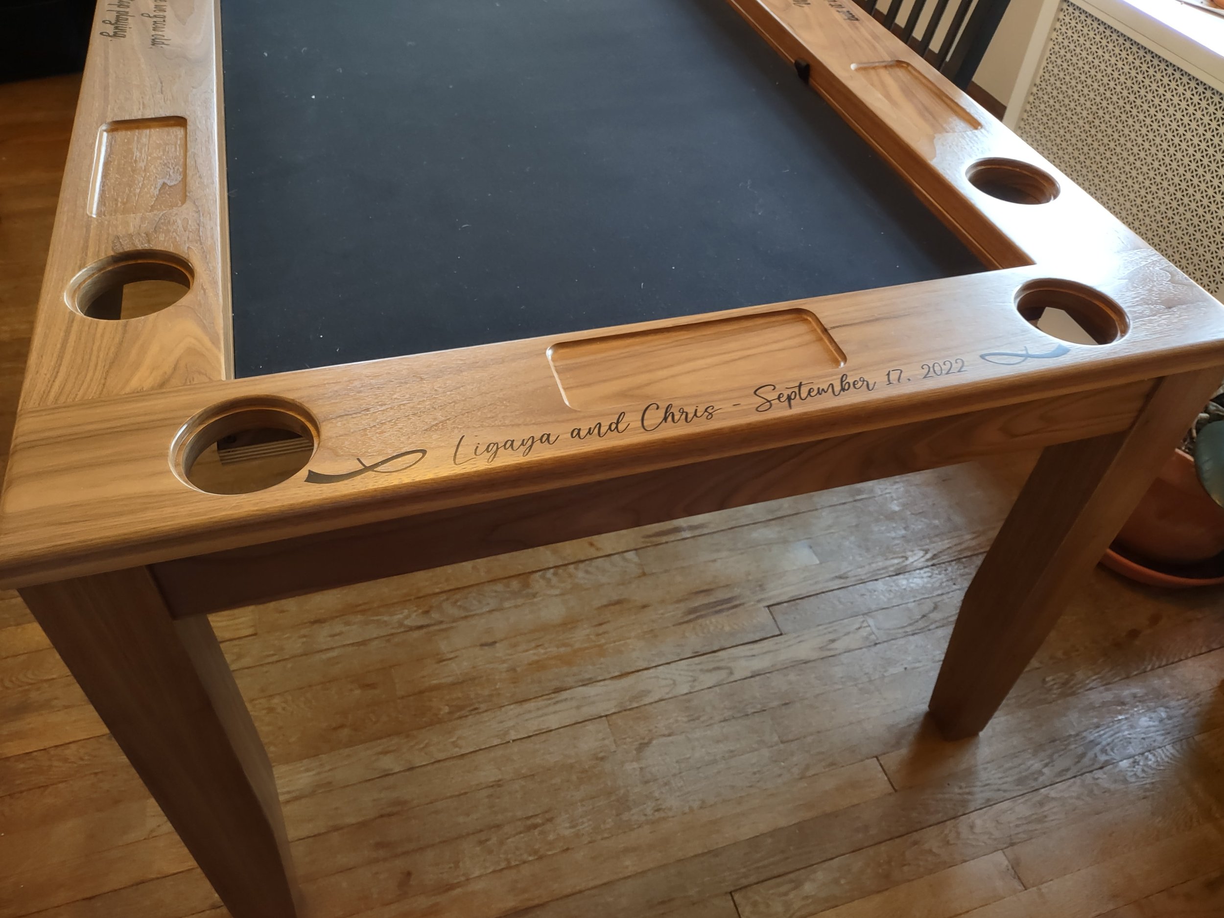 Close up view of a custom engraved armrest on a walnut boar game table