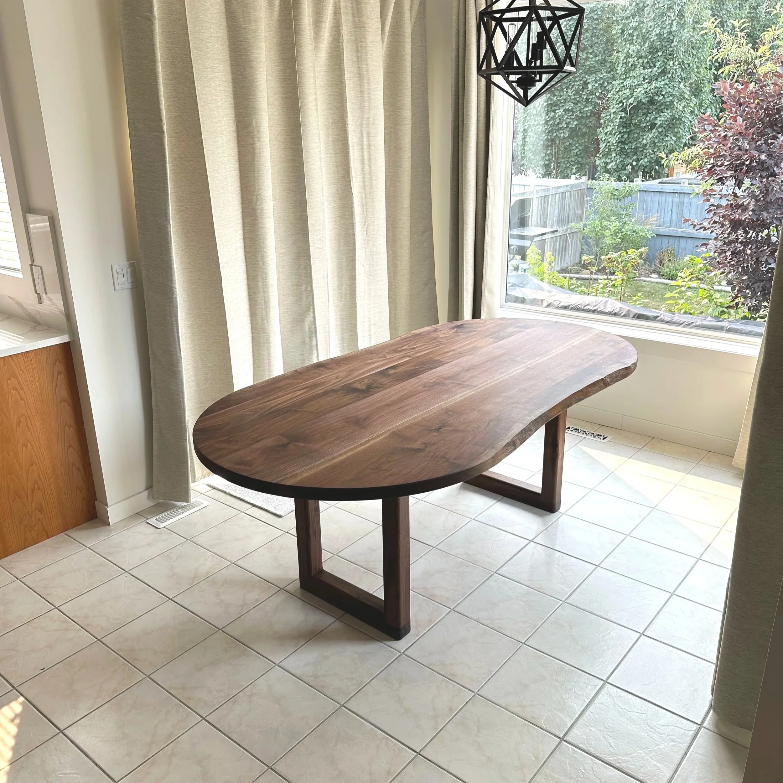 corner view of a walnut live edge dining table with full rounded ends 