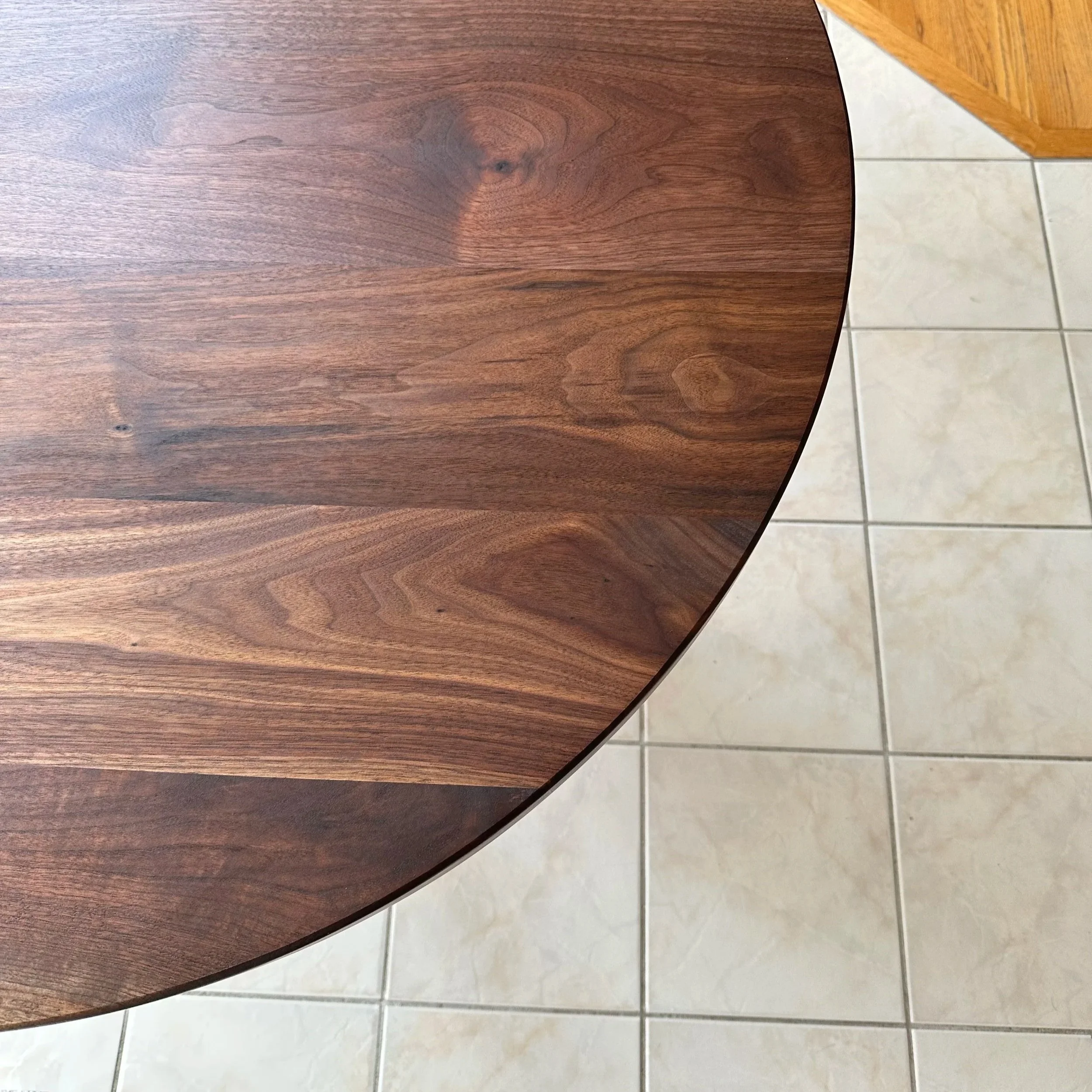 End view of the rounded end of a walnut dining table