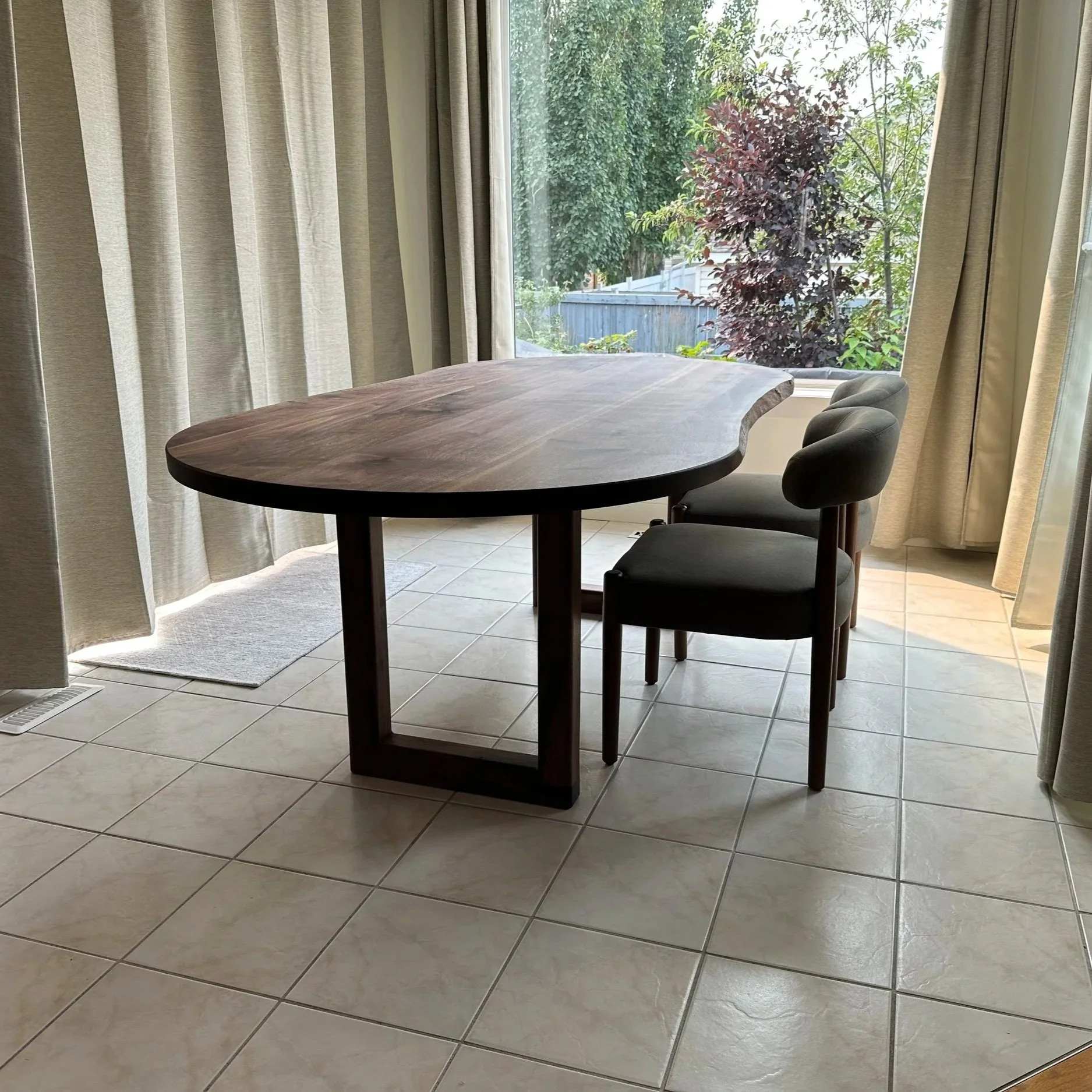 Lower corner view of the dining table showcasing the tabletop and the legs with the chairs on the side