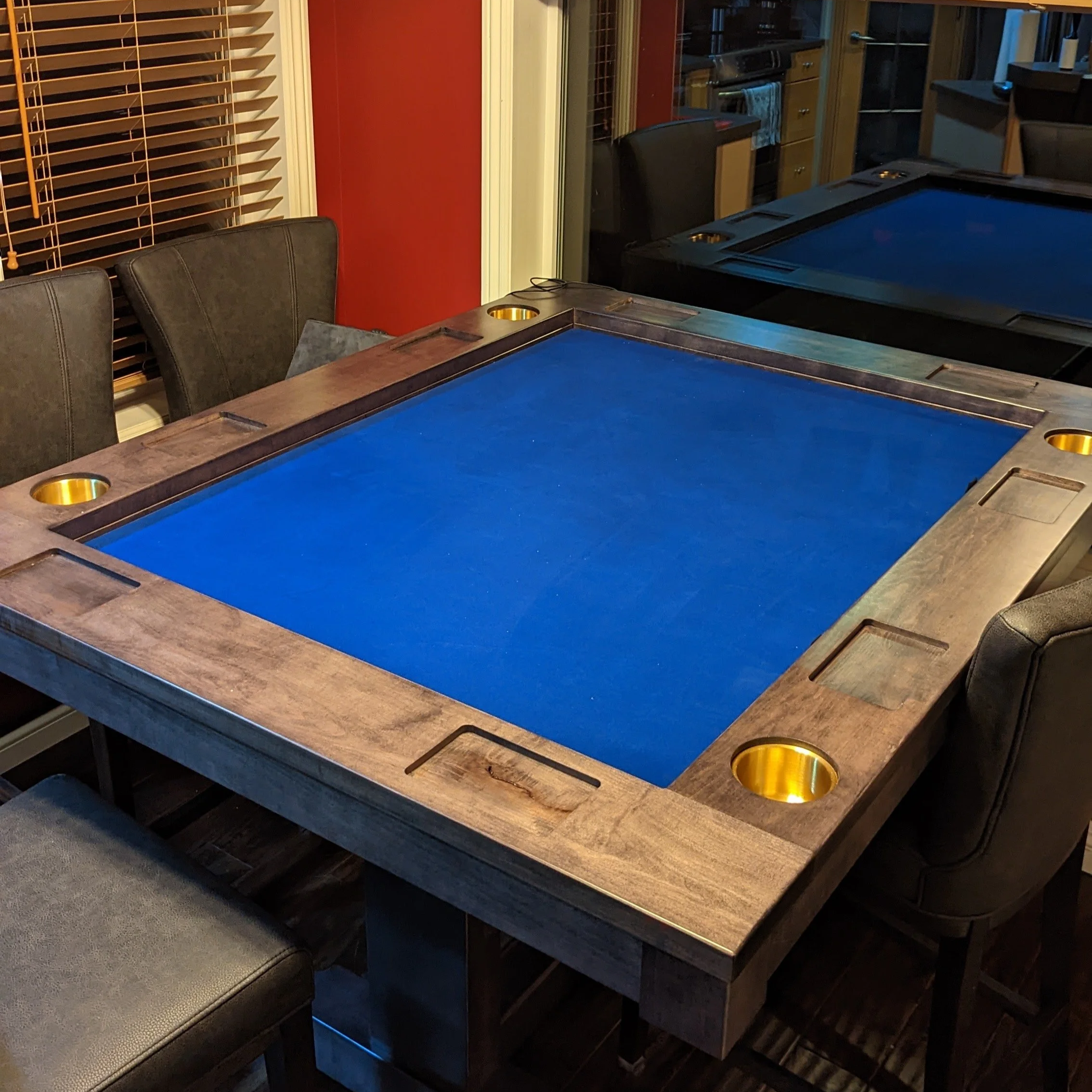 View from the corner of a stained game table with pockets in the armrest and brass cupholders