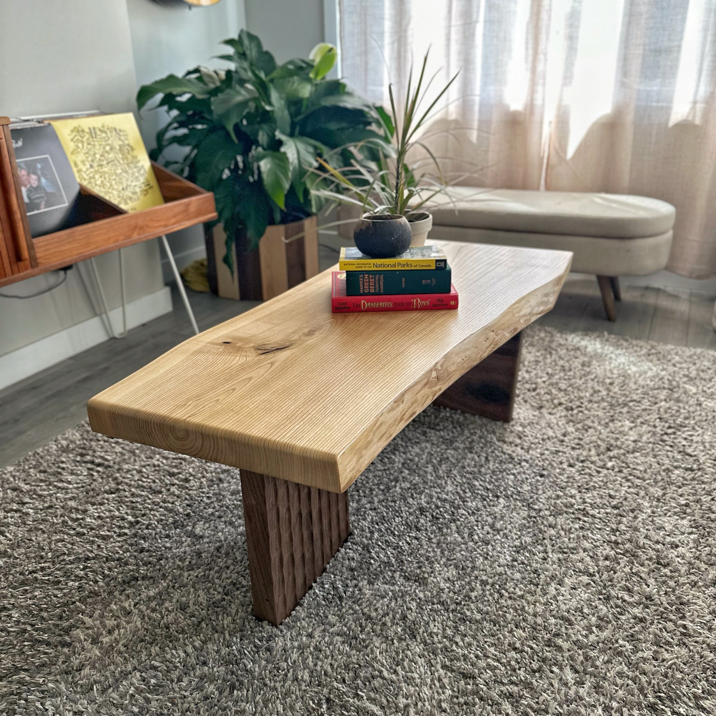 corner view of a ash and walnut coffee table with a live edge ash top and textured walnut base