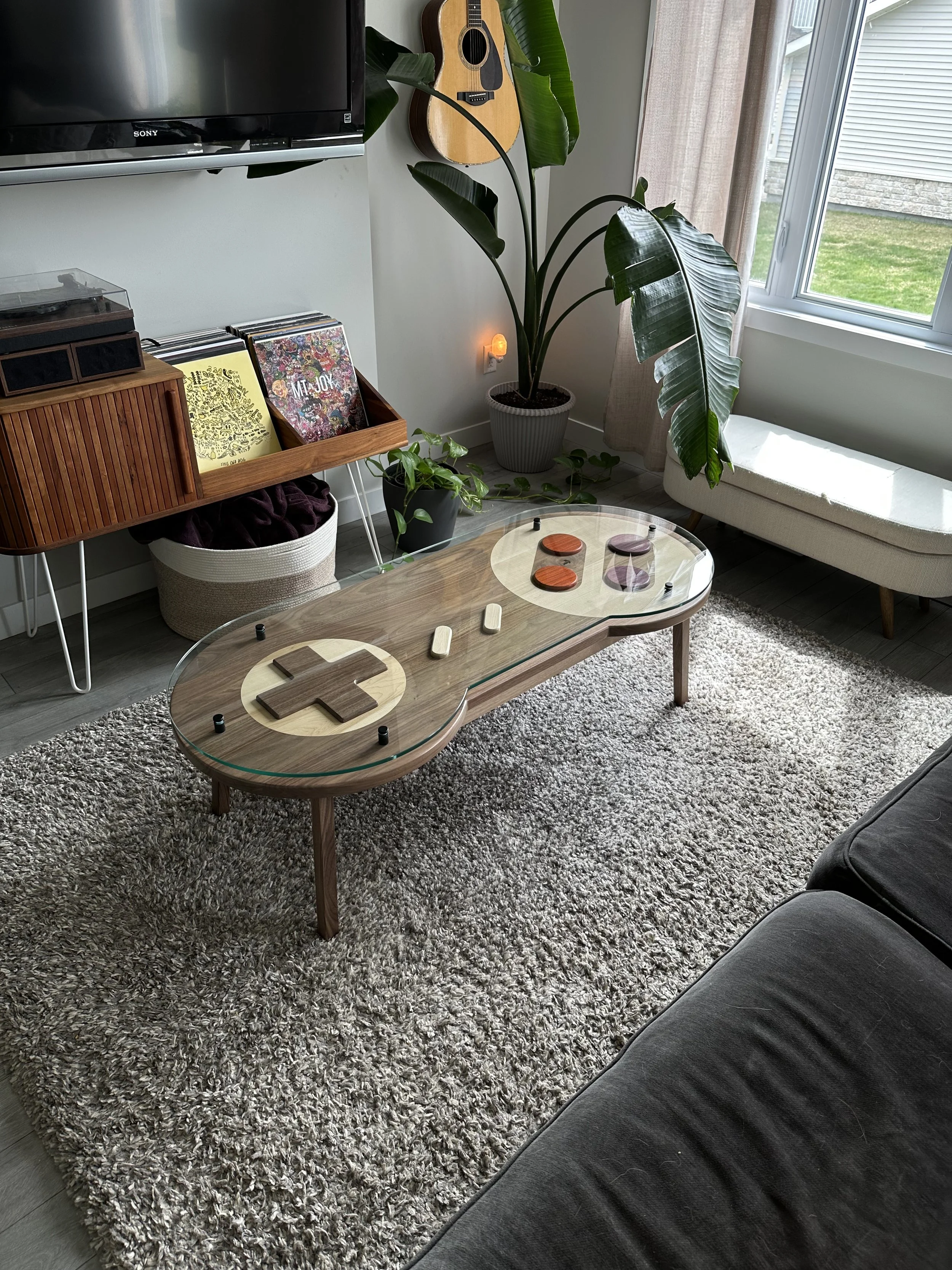 A Nintendo inspired SNES controller coffee table using natural colored woods to achieve the different buttons and accent pieces covered with a thick piece of glass