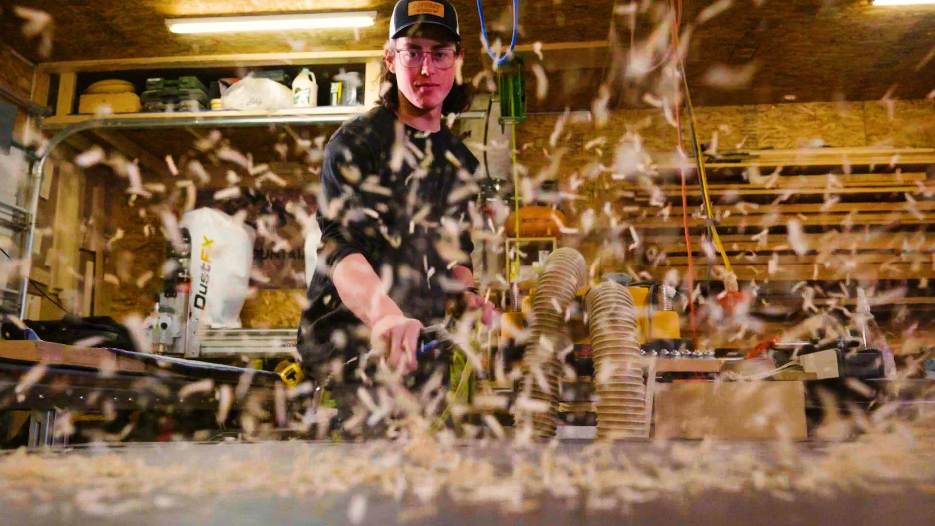 Harley Griffin owner of Stone Mountain Projects bases in Calgary Alberta spraying sawdust off his workbench using an air compressor