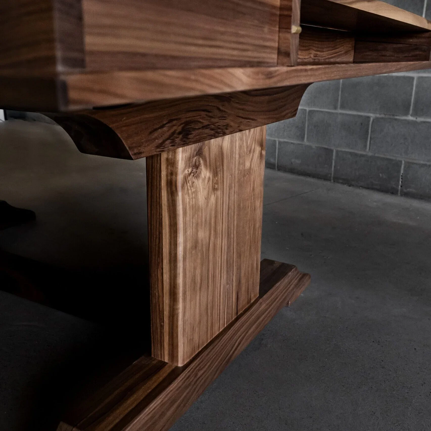 detail view of a walnut trestle base on a player station table designed by Stone Mountain Projects in Calgary Alberta