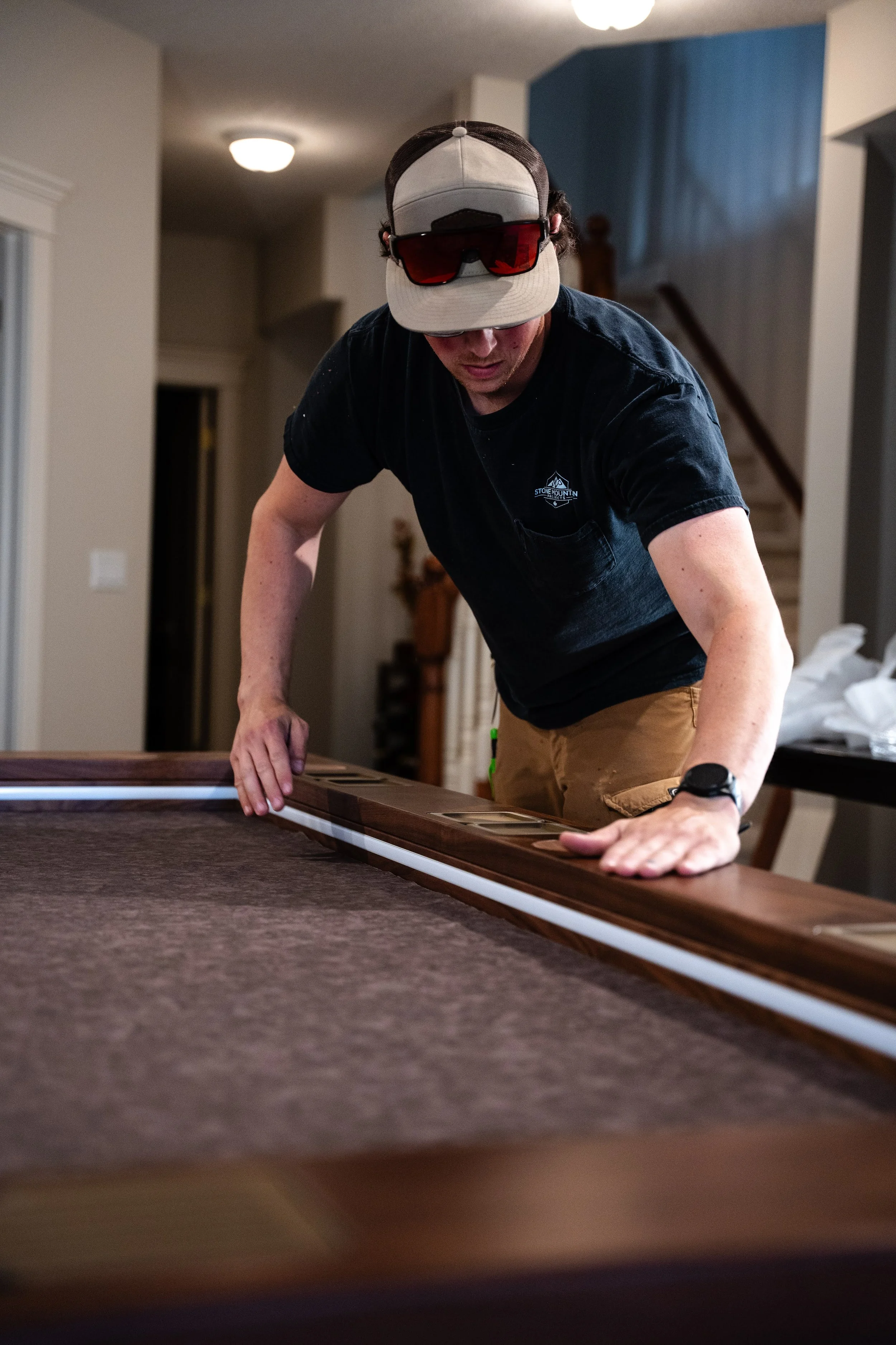 An in action shot of Harley Griffin owner of Stone Mountain Projects wiping down the armrest of a custom game table