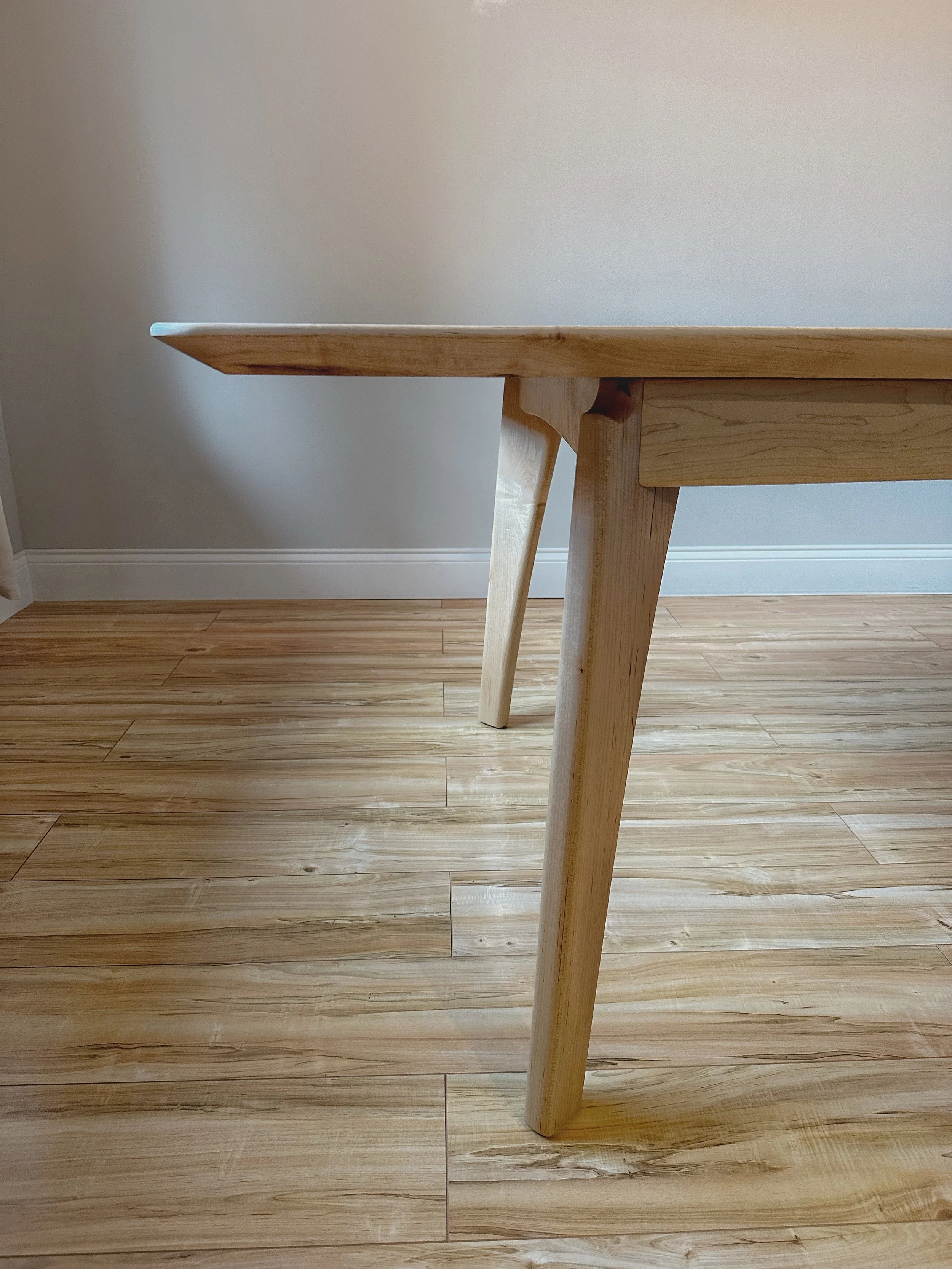 A side view of the custom curved legs and large under bevel on the tabletop giving it a lighter but sturdy feel