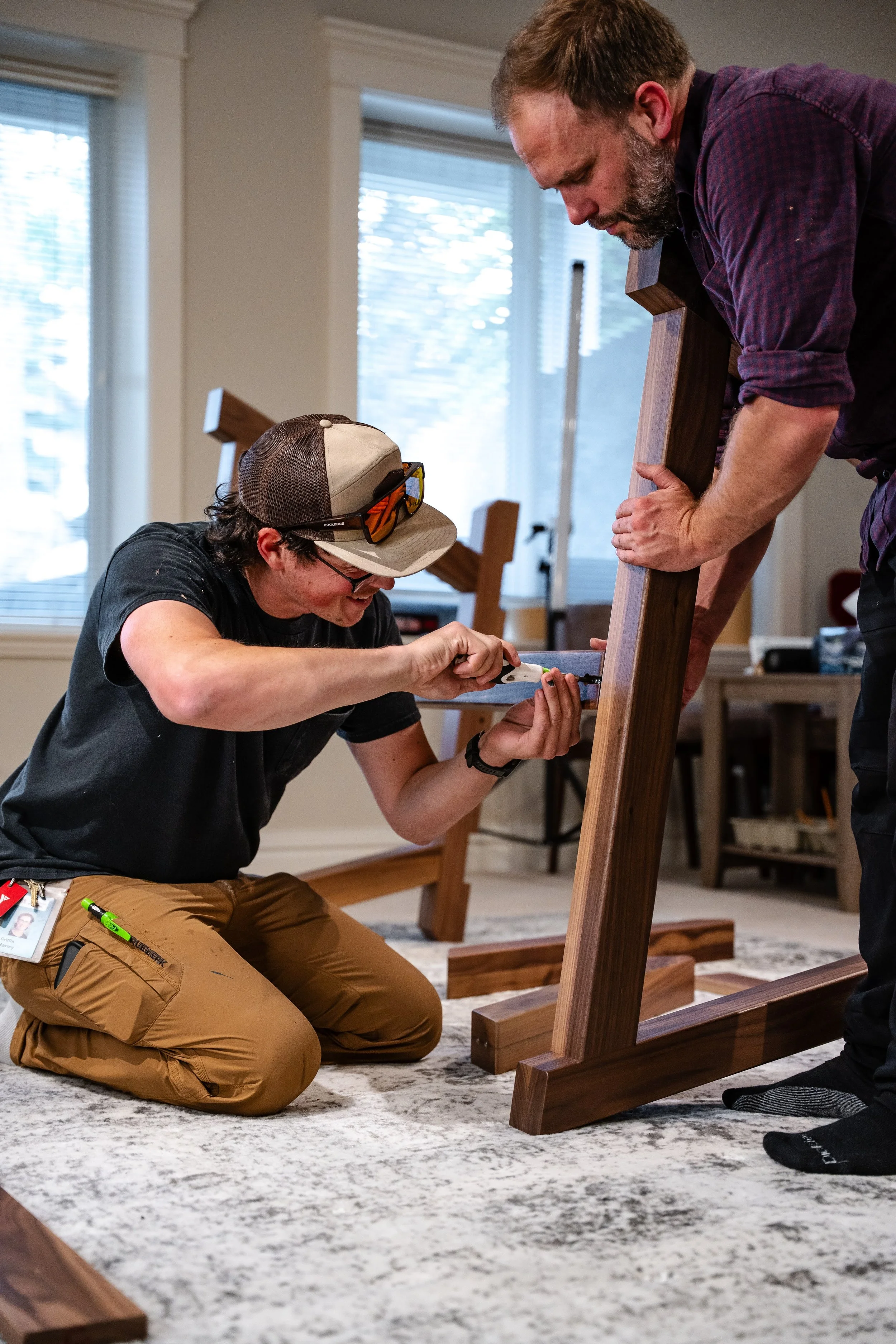 Harley Griffin owner of Stone Mountain Projects and a helper installing bolts on a table base