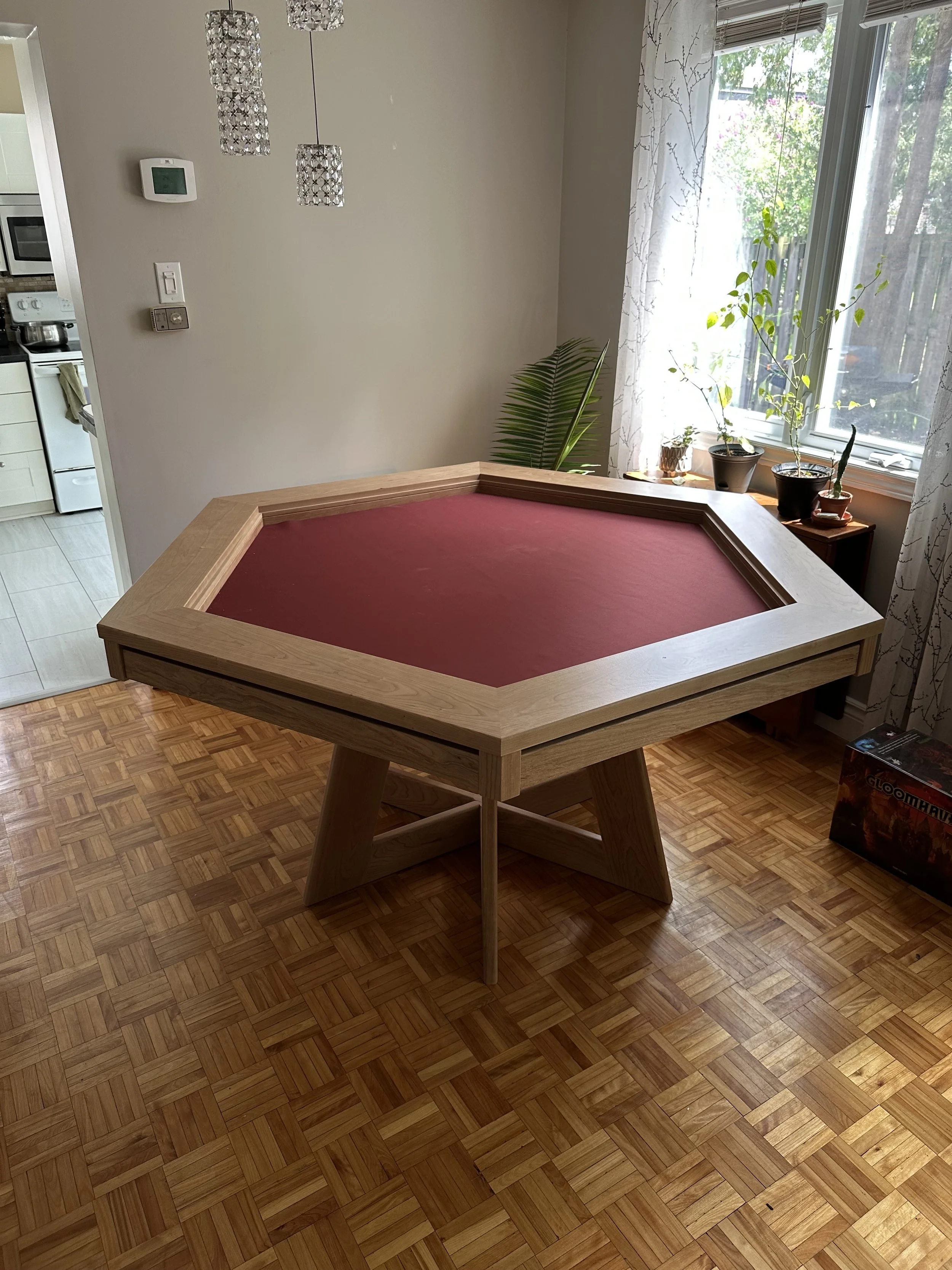wide view of a hexagon game table crafted in cherry with a burgundy rolling mat and interlocking pedestal base