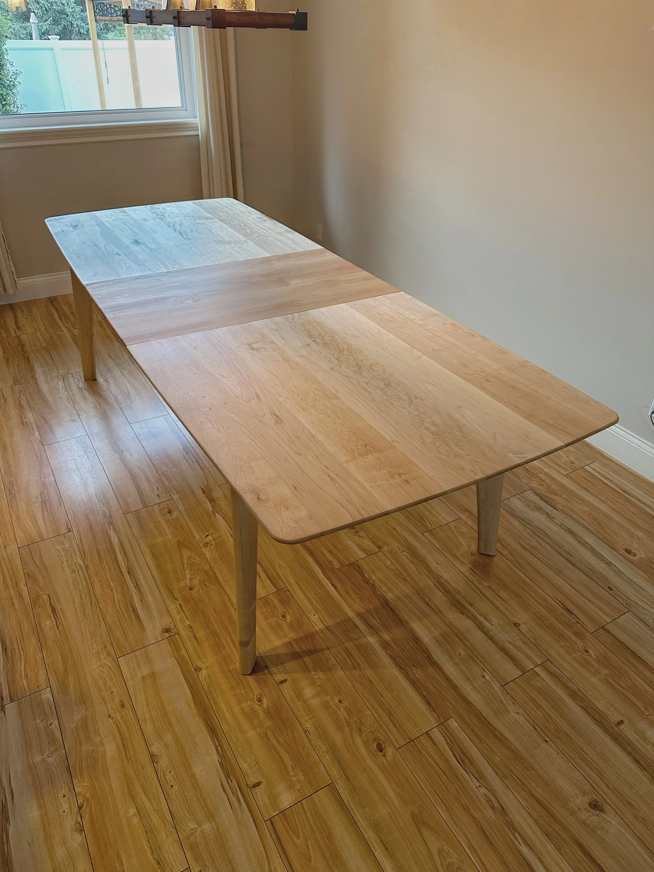 Extendable maple dining table with rounded corners and tapered custom curved legs