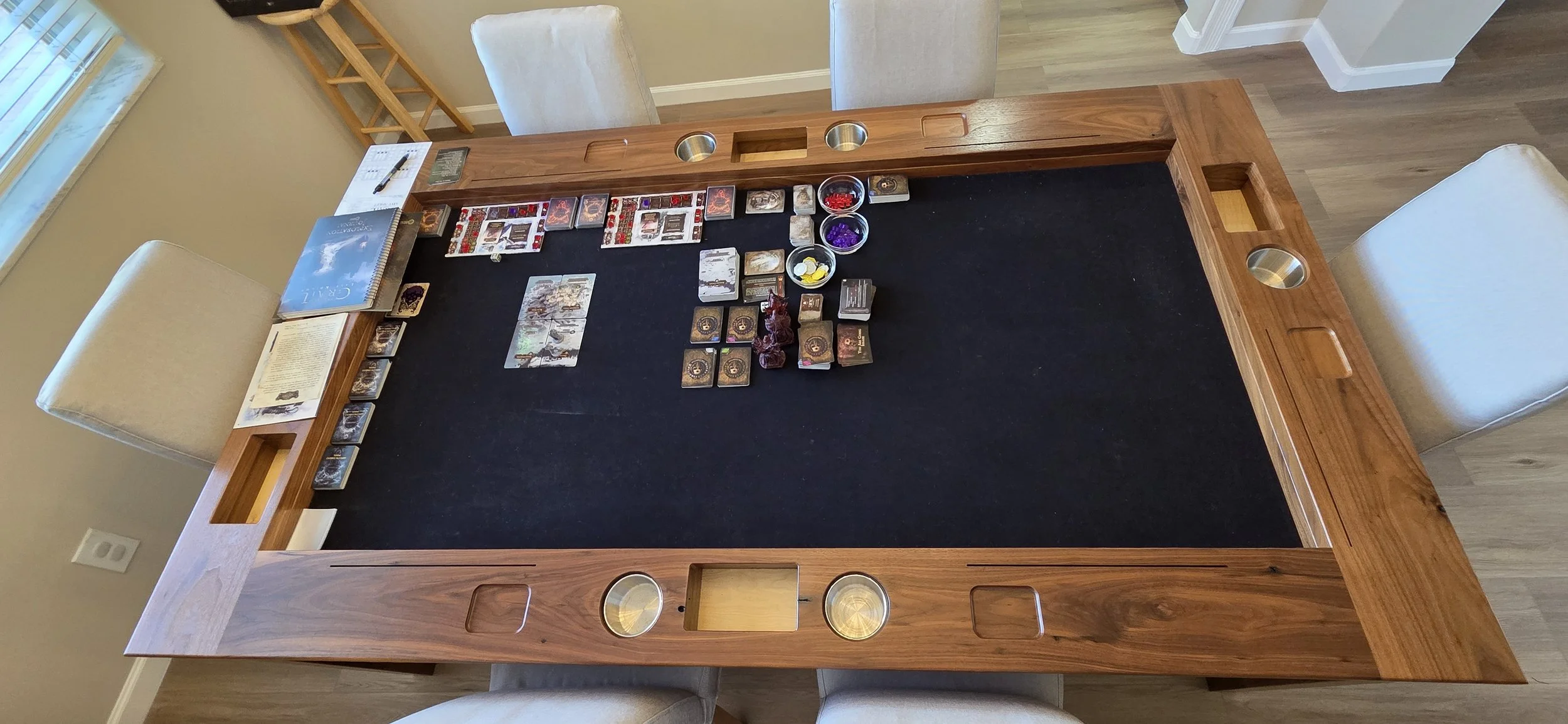 Top down view of a board game setup on a black neoprene mat on a walnut board game table
