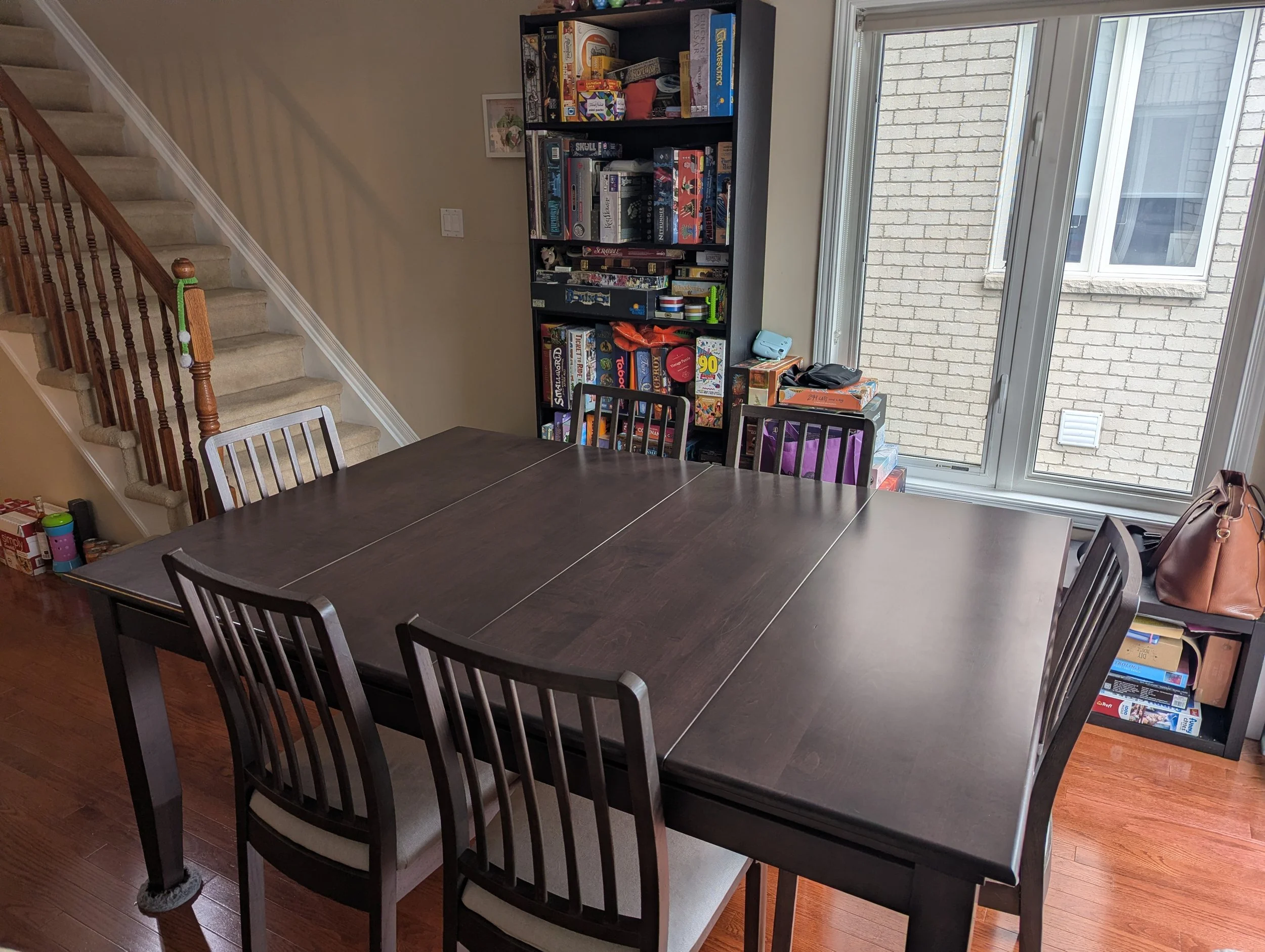 A side view of the game table with the stained table toppers installed with a shelving unit full of board games behind it