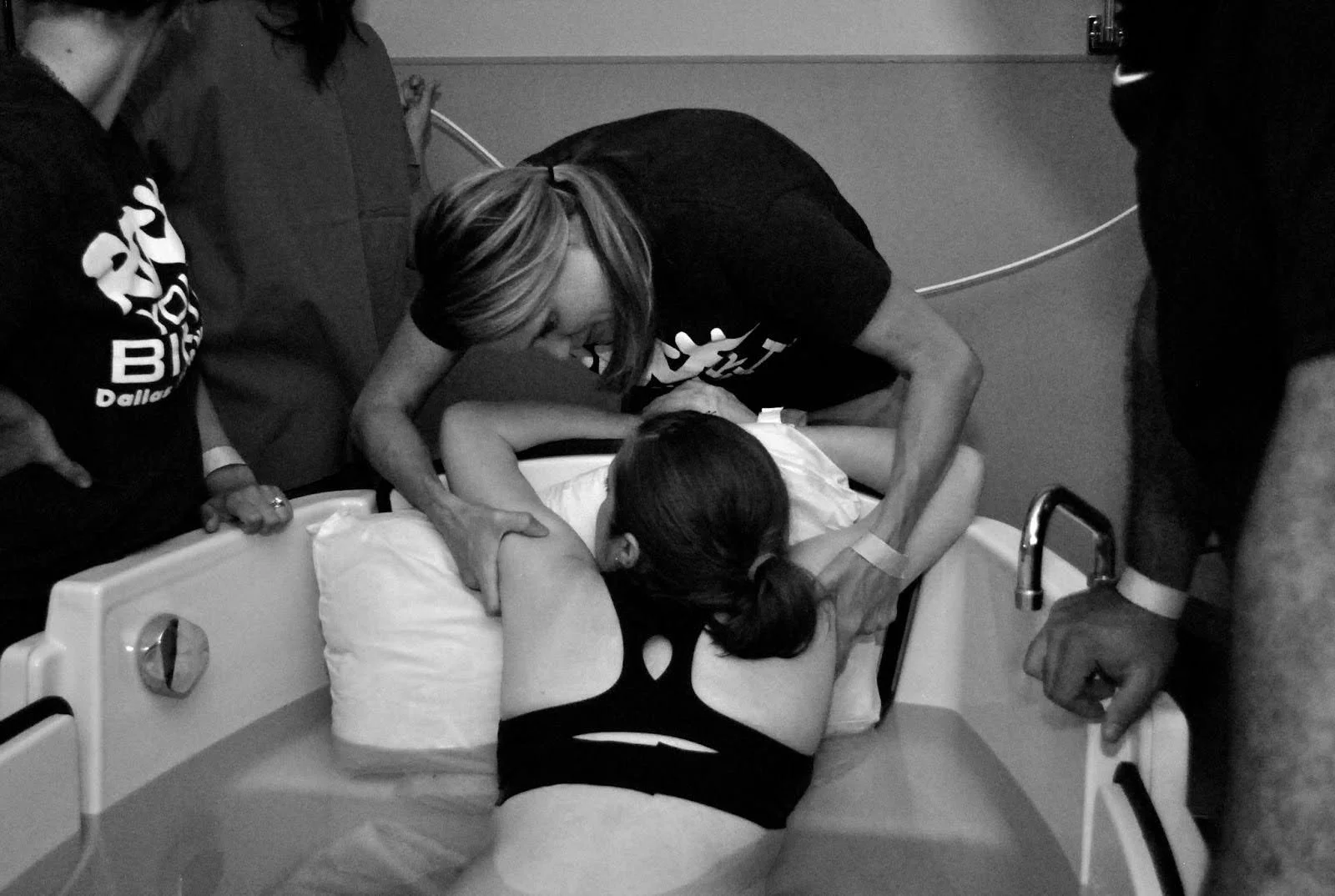 A woman giving birth in a hospital bed, surrounded by medical staff assisting during labor.