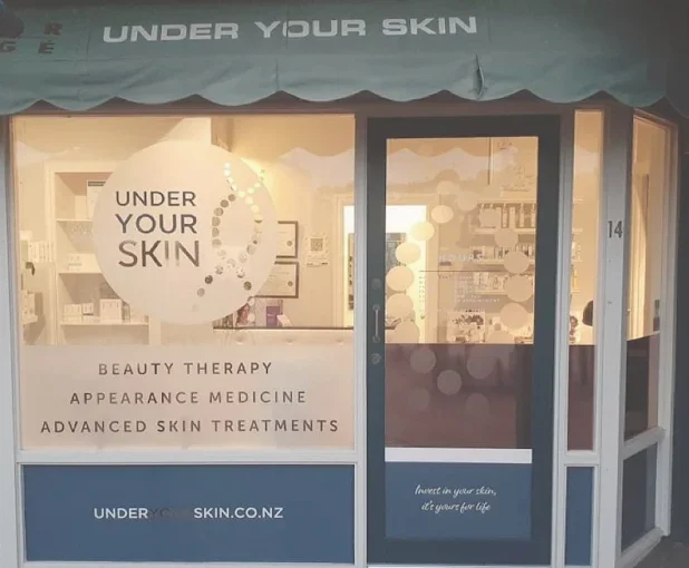 Exterior storefront of a beauty clinic named 'Under Your Skin' with signage indicating they offer beauty therapy, appearance medicine, and advanced skin treatments.