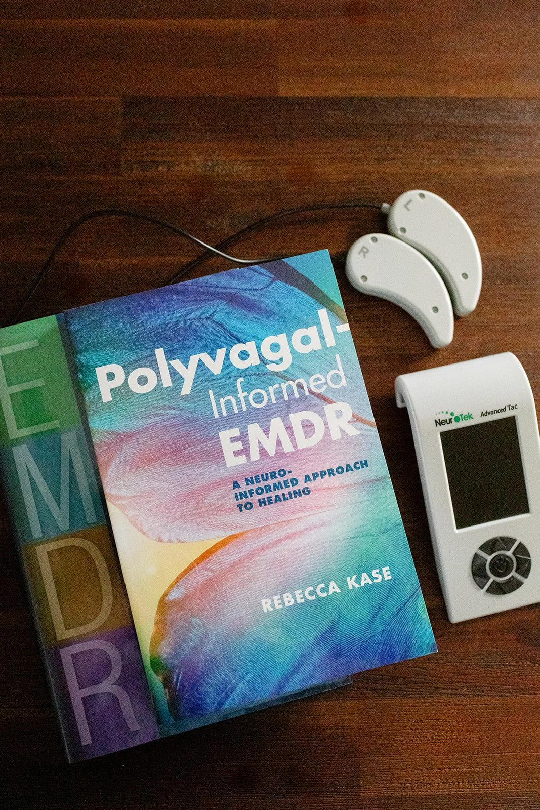 Polyvagal-informed EMDR book and bilateral stimulation devices used in trauma therapy