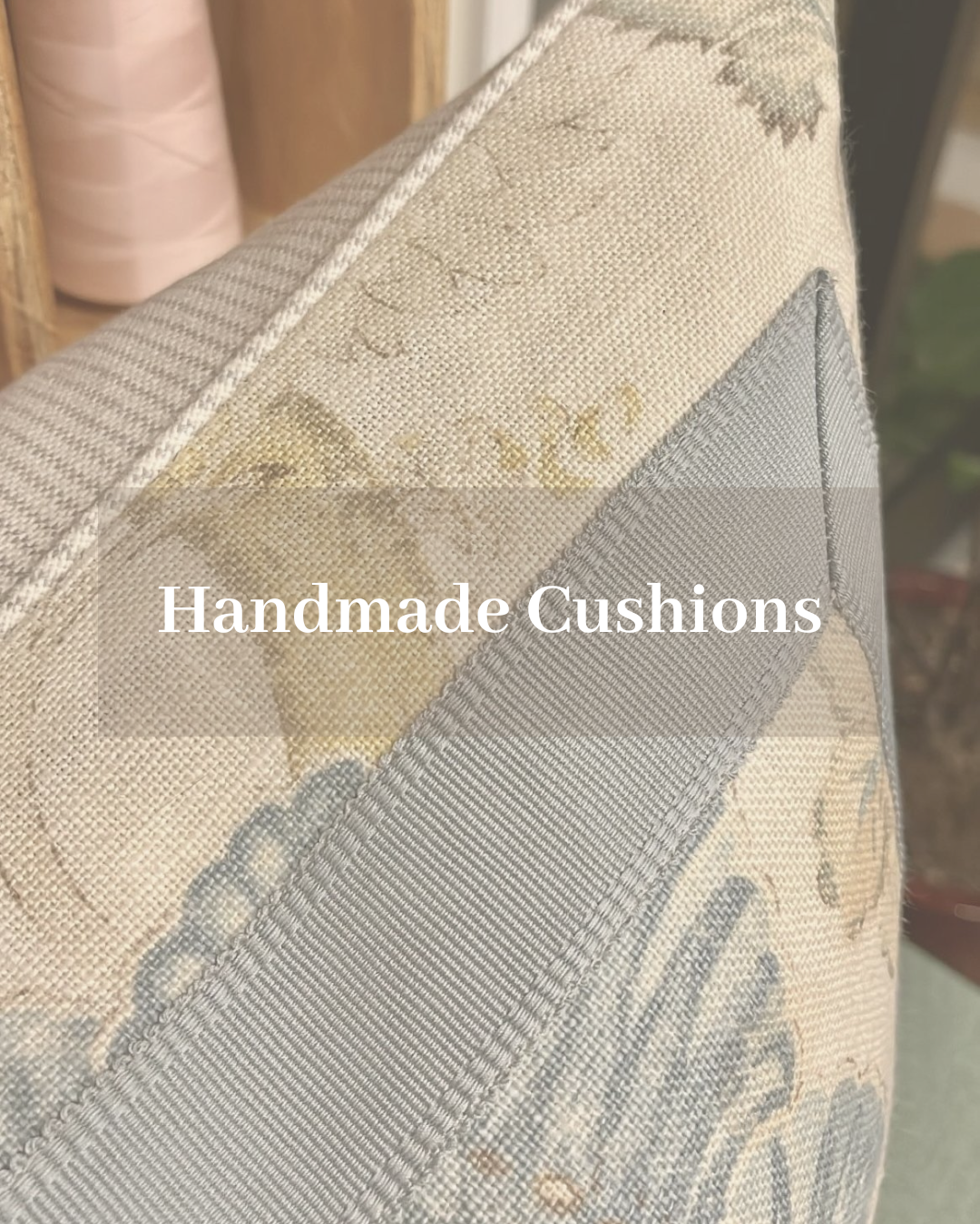 Interior of a living room with antique decor, including a tall wooden clock, a table with vintage books, flowers, and a table lamp with a blue shade. The room has large windows with floral curtains.