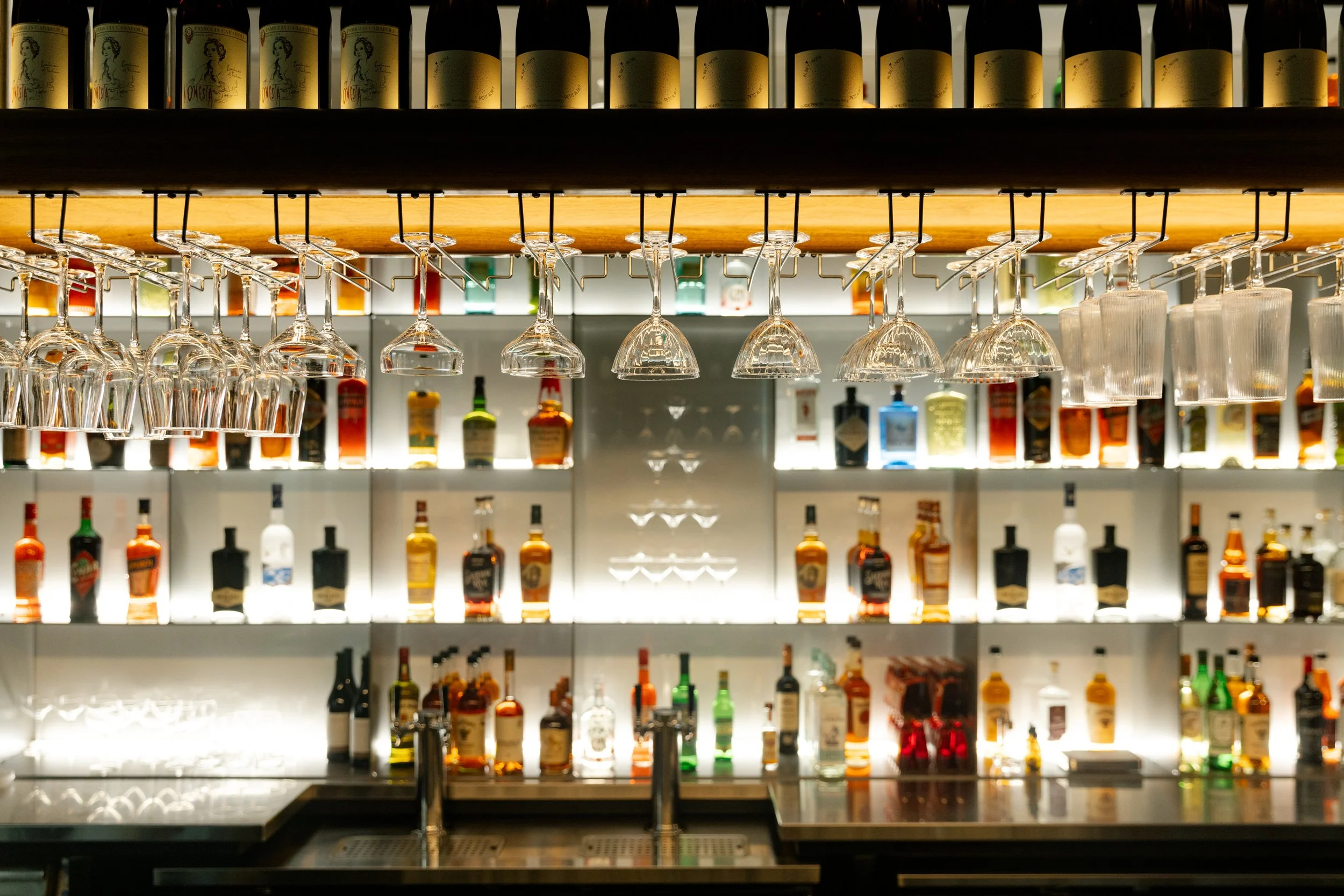 Bar with shelves of liquor bottles and hanging upside-down wine glasses