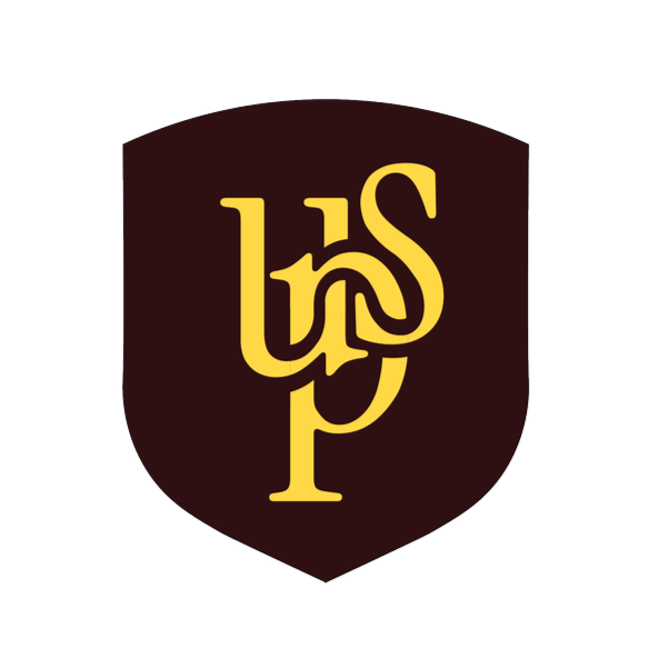 A man with curly dark hair, glasses, and a beard, wearing a black sweater, looking slightly to the side with a thoughtful expression, in a room with a white wall and a plant in the background.