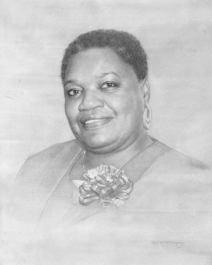 A man with dark, curly hair, glasses, and a beard, sitting indoors, looking thoughtfully to the side.