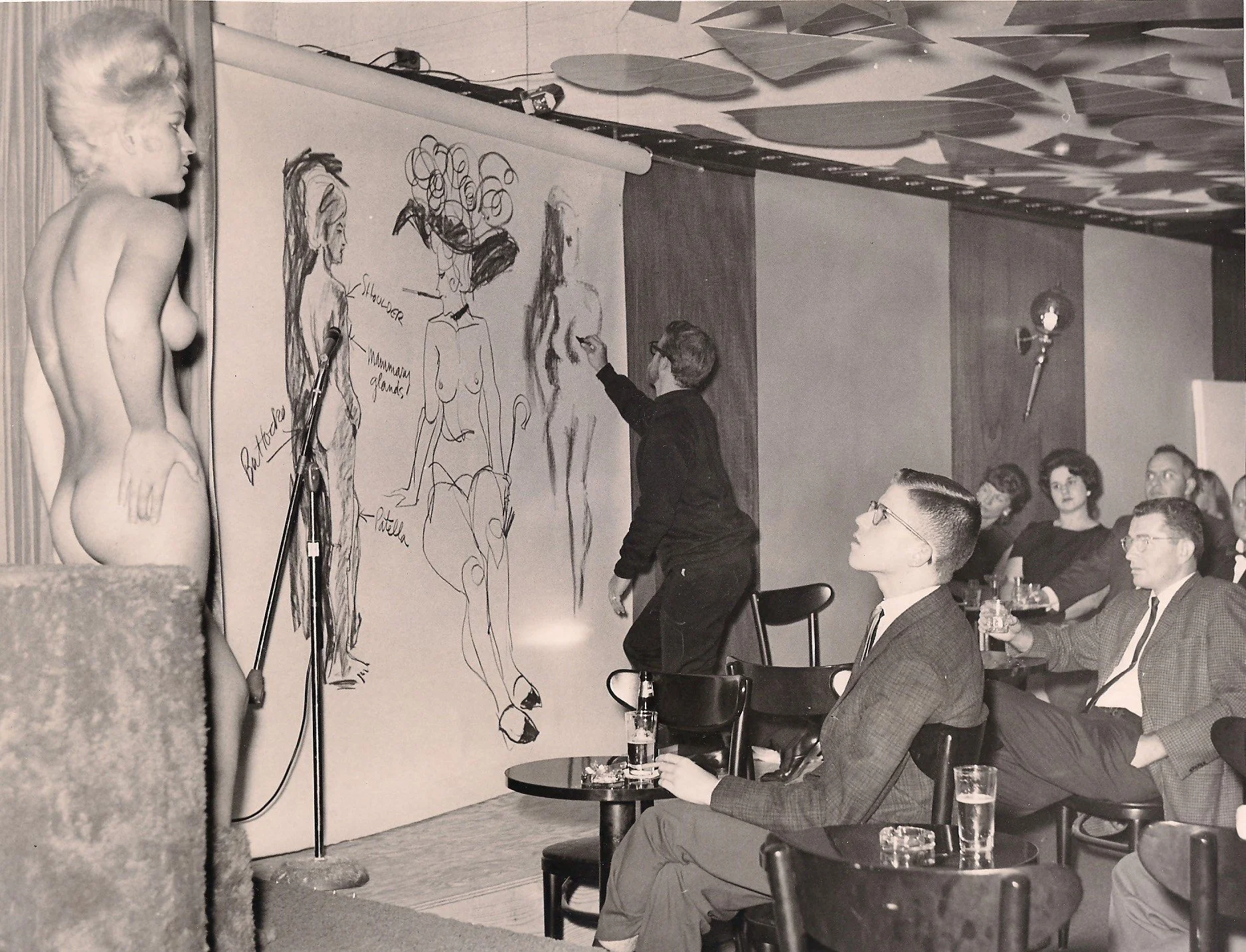 Photo of Robert McClay sketching a nude model for a nightclub act at "Mr. Wonderful" club in San Francisco in 1964.