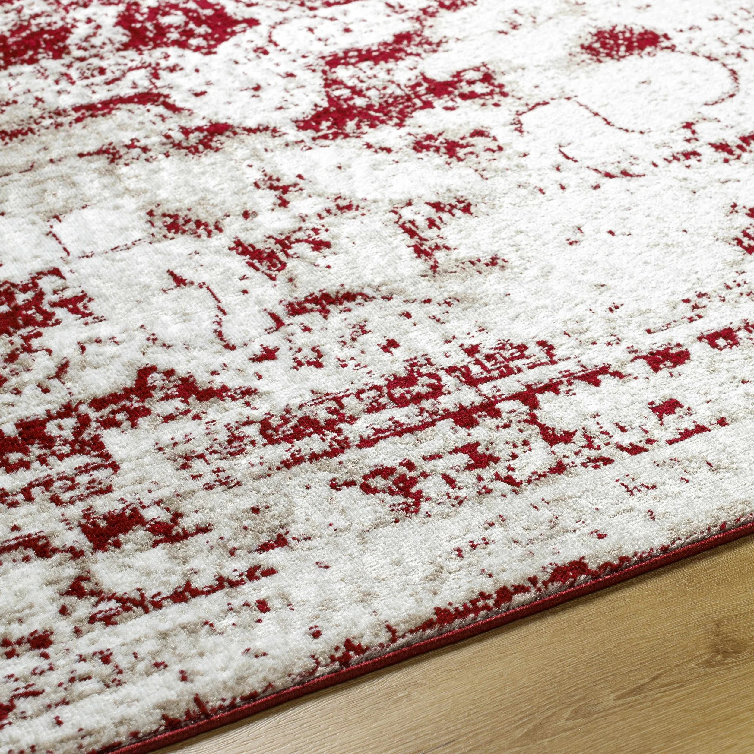 Close-up of a red and white patterned area rug on a wooden floor.
