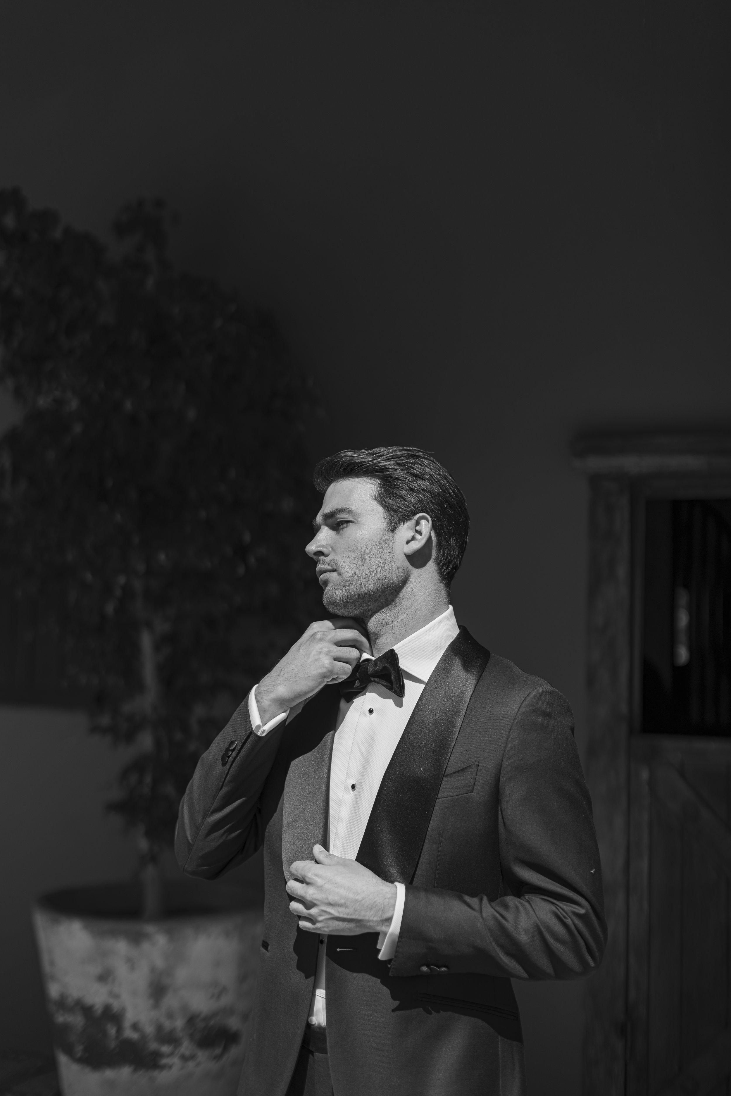 Hombre en traje formal ajustándose la corbata, en un ambiente interior