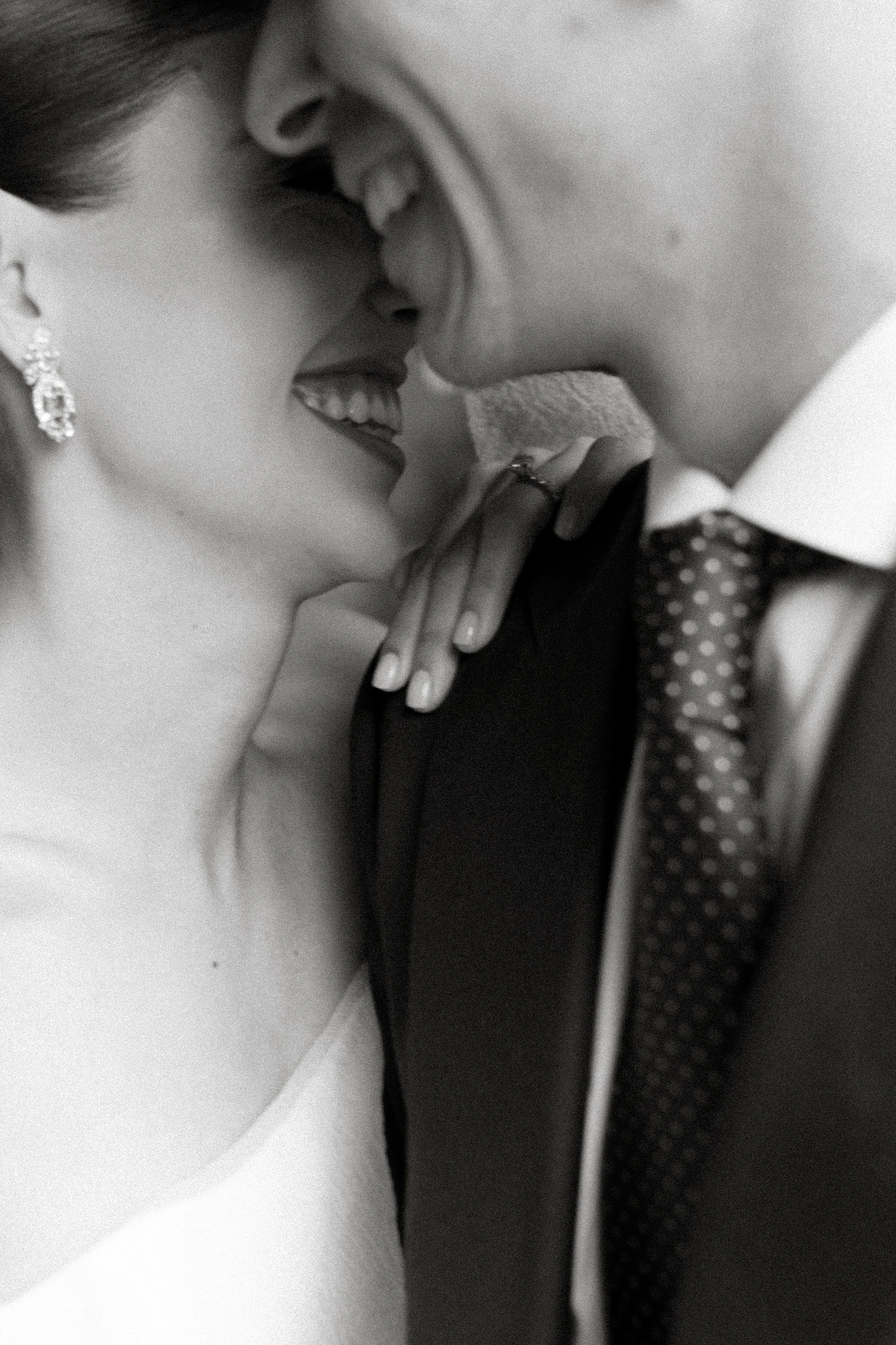 Una pareja de novios en un momento romántico y cercano, sonriendo y casi tocándose la frente.